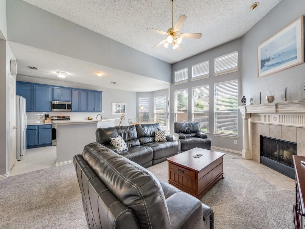 Open-concept living area featuring a vaulted ceiling and a fireplace with a mantel