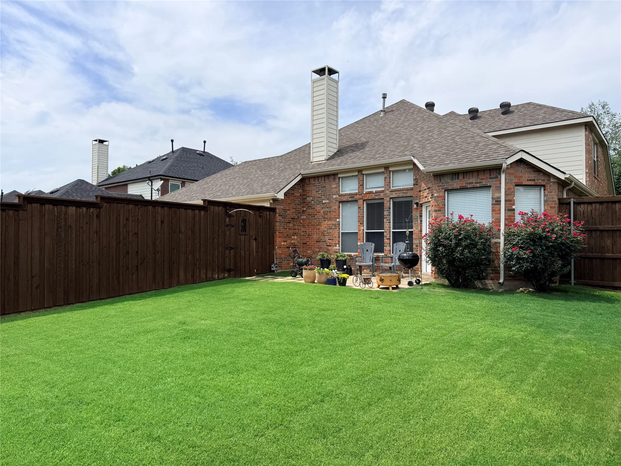 Expansive backyard featuring a lush green lawn and mature perimeter landscaping