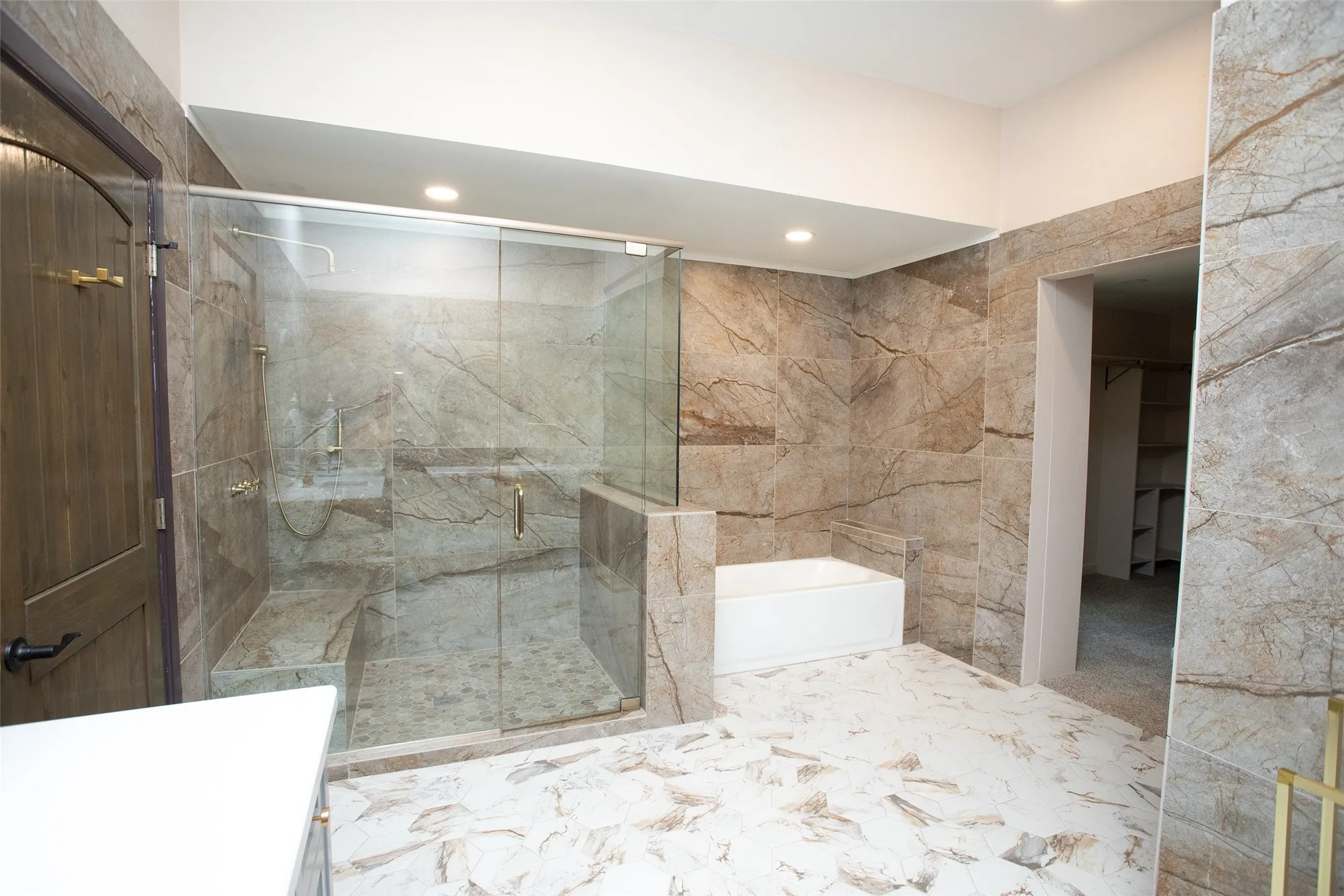 The ensuite bath is designed with scale and style in mind, featuring dual vanities, extensive tile work, a walk-in shower, and a separate soaking tub for a true spa-like experience.
The adjoining dressing area includes generous storage, open shelving, and space for a vanity or dressing station, creating a functional and well-appointed extension of the primary suite.