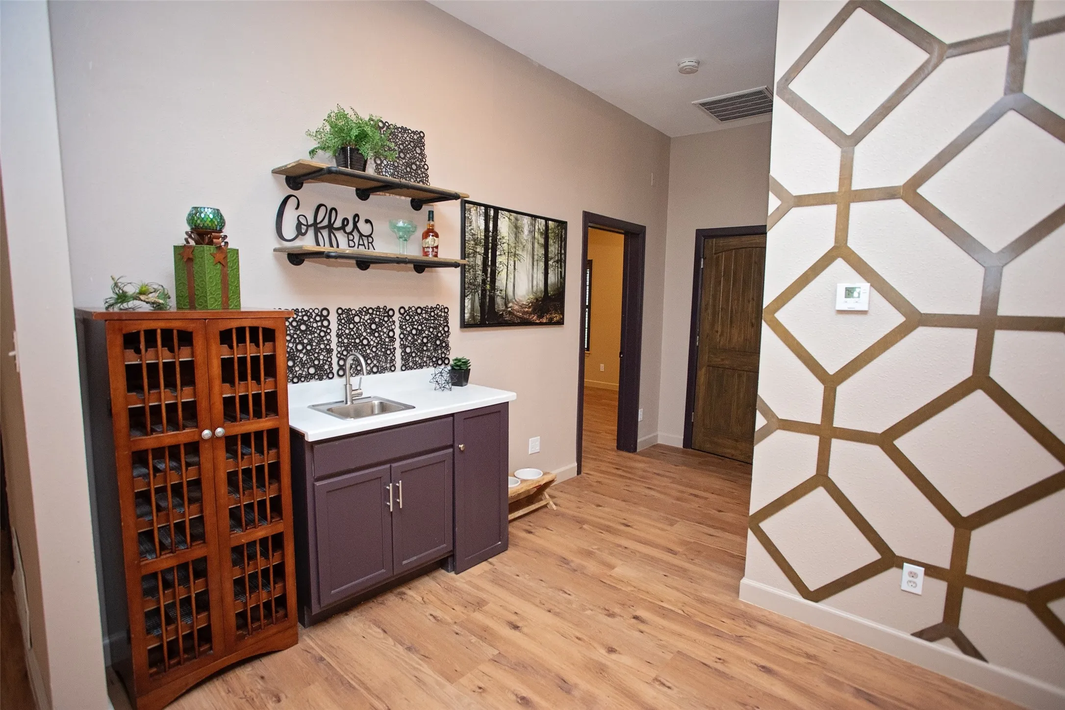 Wet bar open to the living, kitchen, and dining areas—featuring a sink, cabinetry, and display shelving, ideal for entertaining and everyday convenience.
