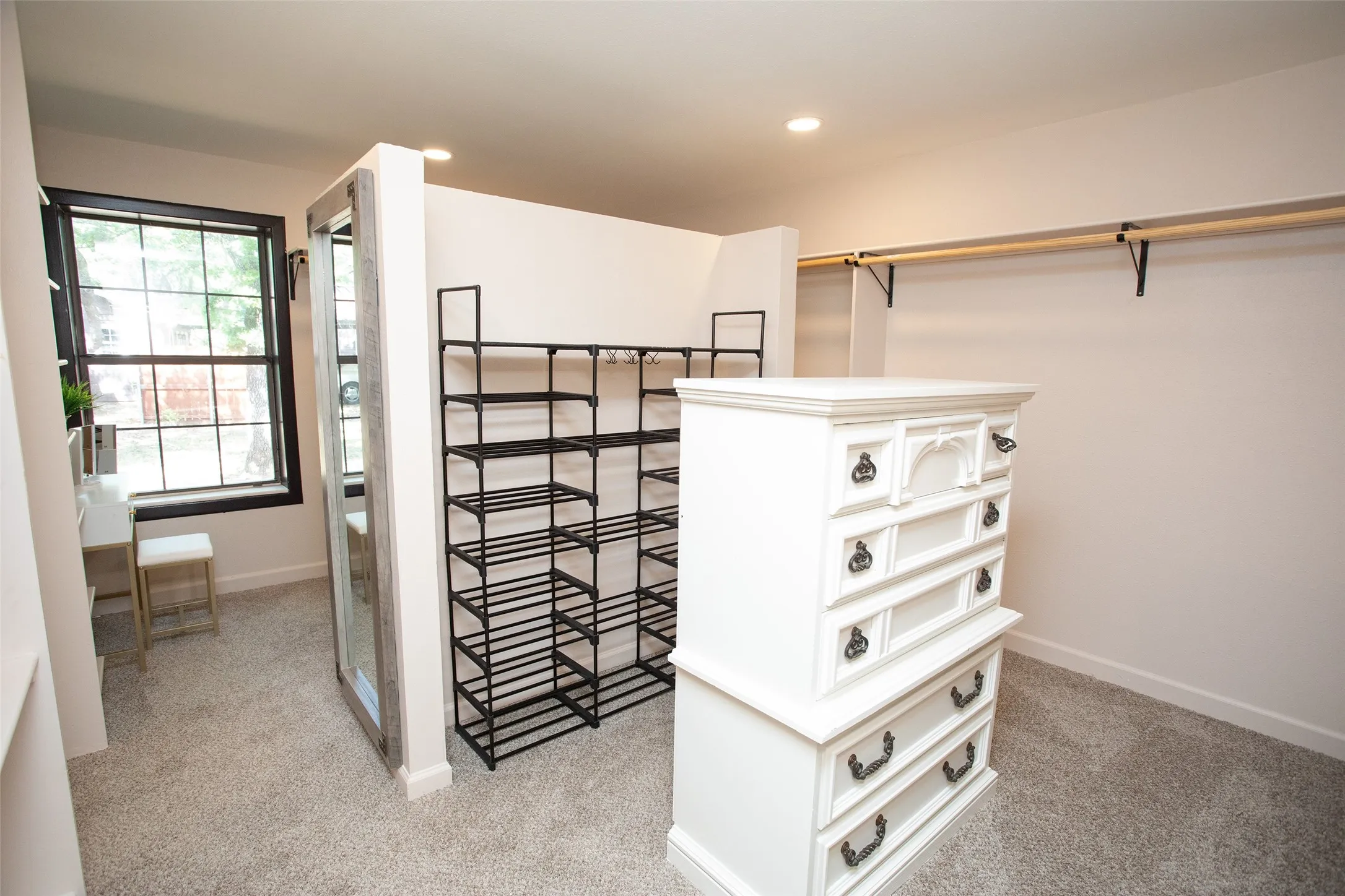 The adjoining dressing area includes generous storage, open shelving, and space for a vanity or dressing station, creating a functional and well-appointed extension of the primary suite.