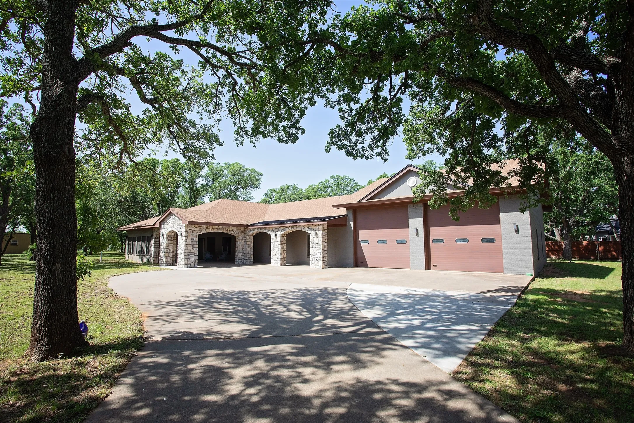 A long, sweeping driveway leads to the home, where stone and brick accents, arched architectural details, and a welcoming covered entry create a strong first impression. The circular drive adds both convenience and elegance, offering ample parking for guests while enhancing the overall approach to the home.Surrounded by established trees and set back from the road, the setting feels private and peaceful, with plenty of room to enjoy the outdoors while maintaining a refined, well-maintained appearance.