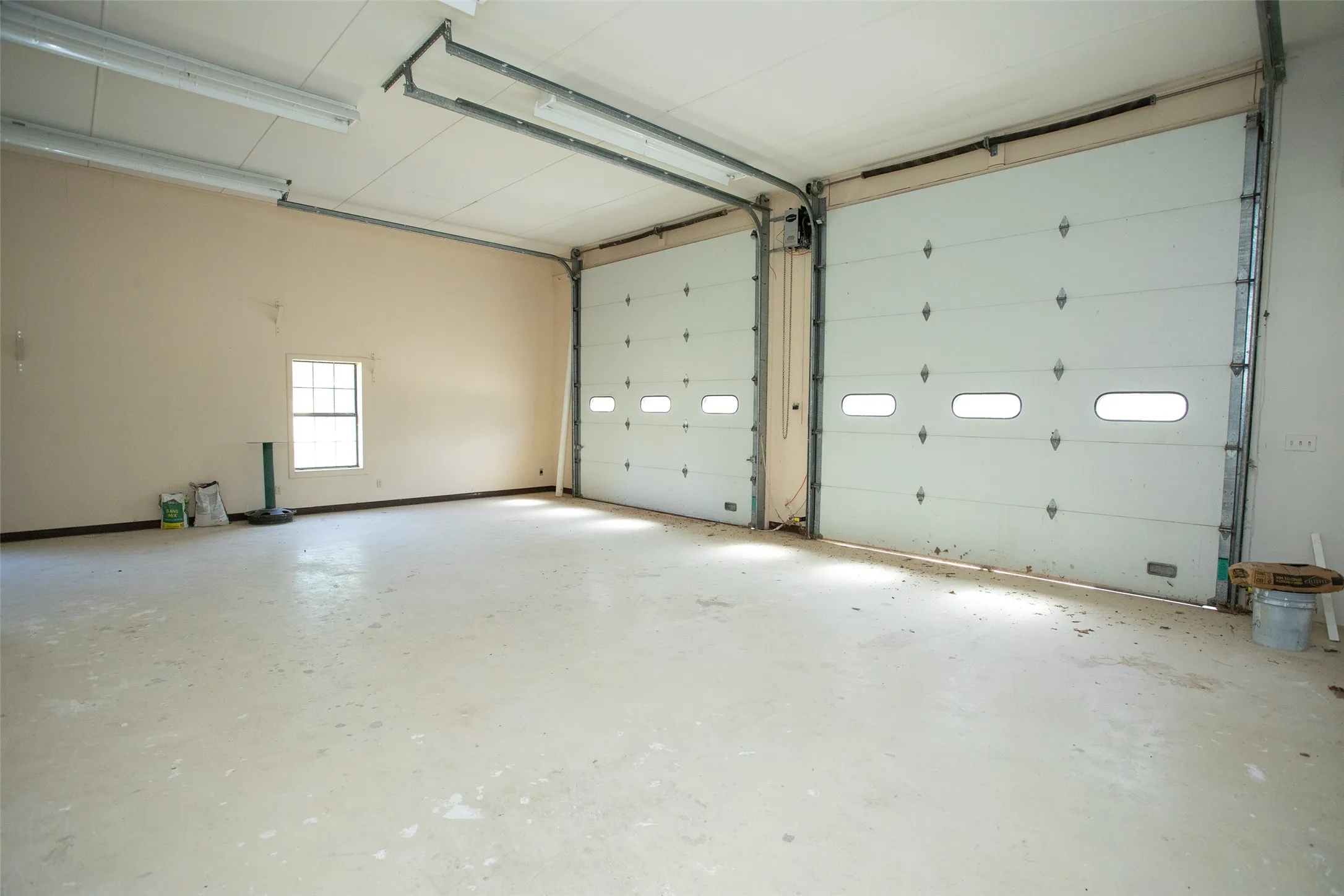 Expansive garage/workshop offering exceptional versatility with approximately 37' in length, 33' in width, and soaring 14' ceilings. Dual overhead doors provide easy access for vehicles, equipment, or recreational storage, while the generous open span allows room for multiple uses—whether for oversized parking, a workshop, or hobby space. Bright overhead lighting and two windows for natural light enhance functionality. Additional storage is available above the primary closet area, maximizing space for seasonal items or long-term organization.