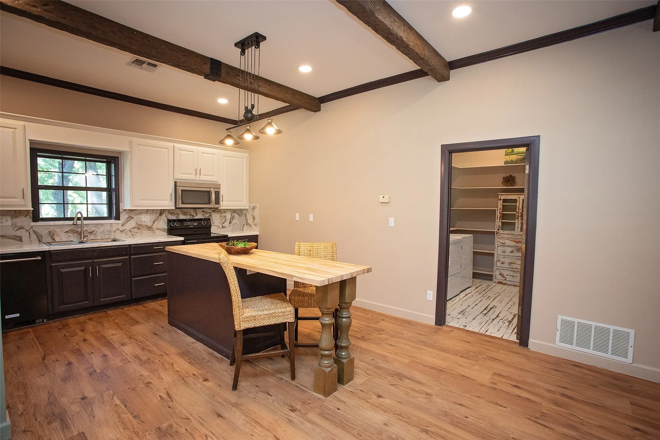 Kitchen view highlighting direct access to the separate utility room for added convenience and functionality. The kitchen offers ample cabinetry, stainless appliances, and a central island for casual seating, all open to the main living areas while keeping the utility space privately tucked away.