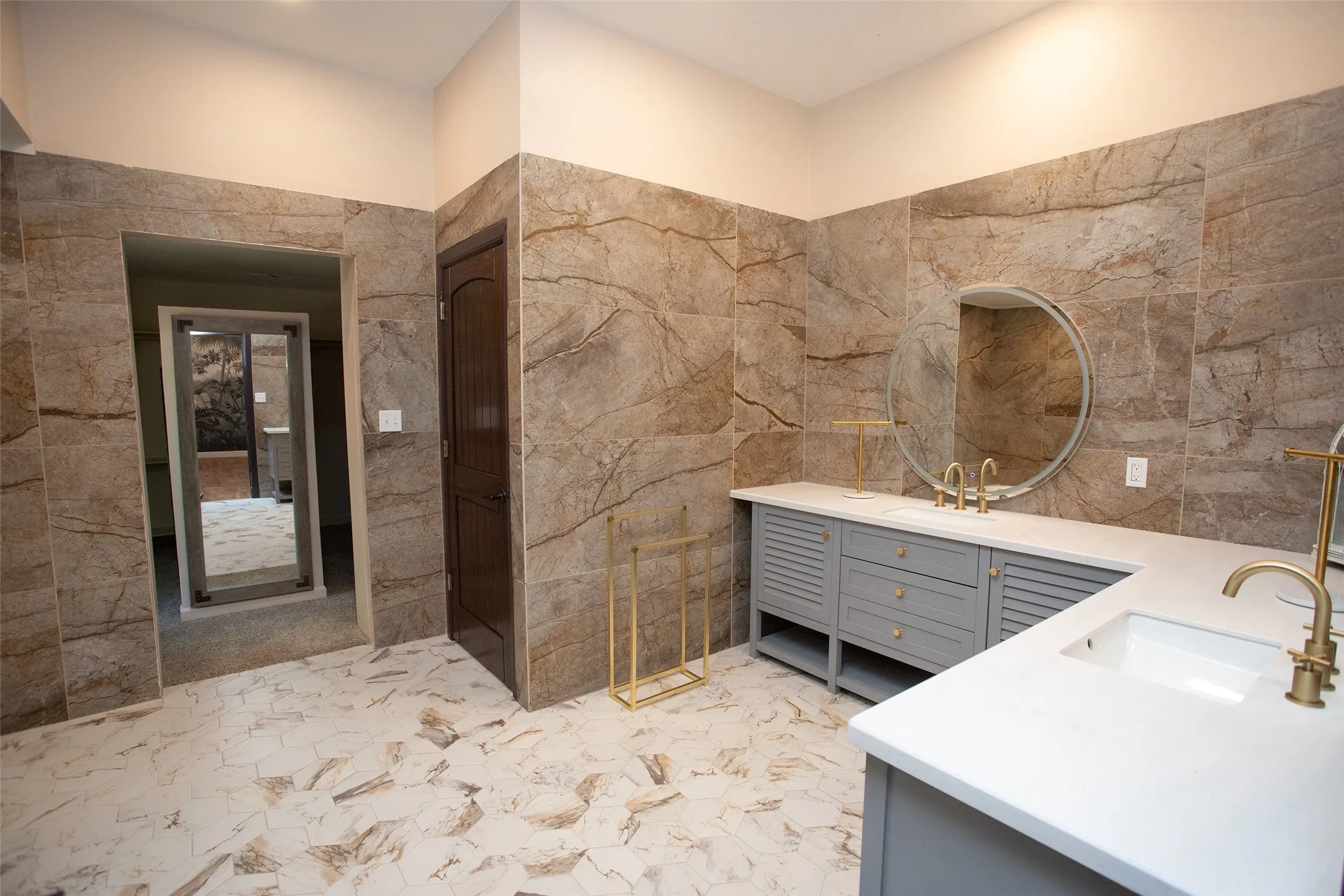 The ensuite bath is designed with scale and style in mind, featuring dual vanities, extensive tile work, a walk-in shower, and a separate soaking tub for a true spa-like experience.
The adjoining dressing area includes generous storage, open shelving, and space for a vanity or dressing station, creating a functional and well-appointed extension of the primary suite.