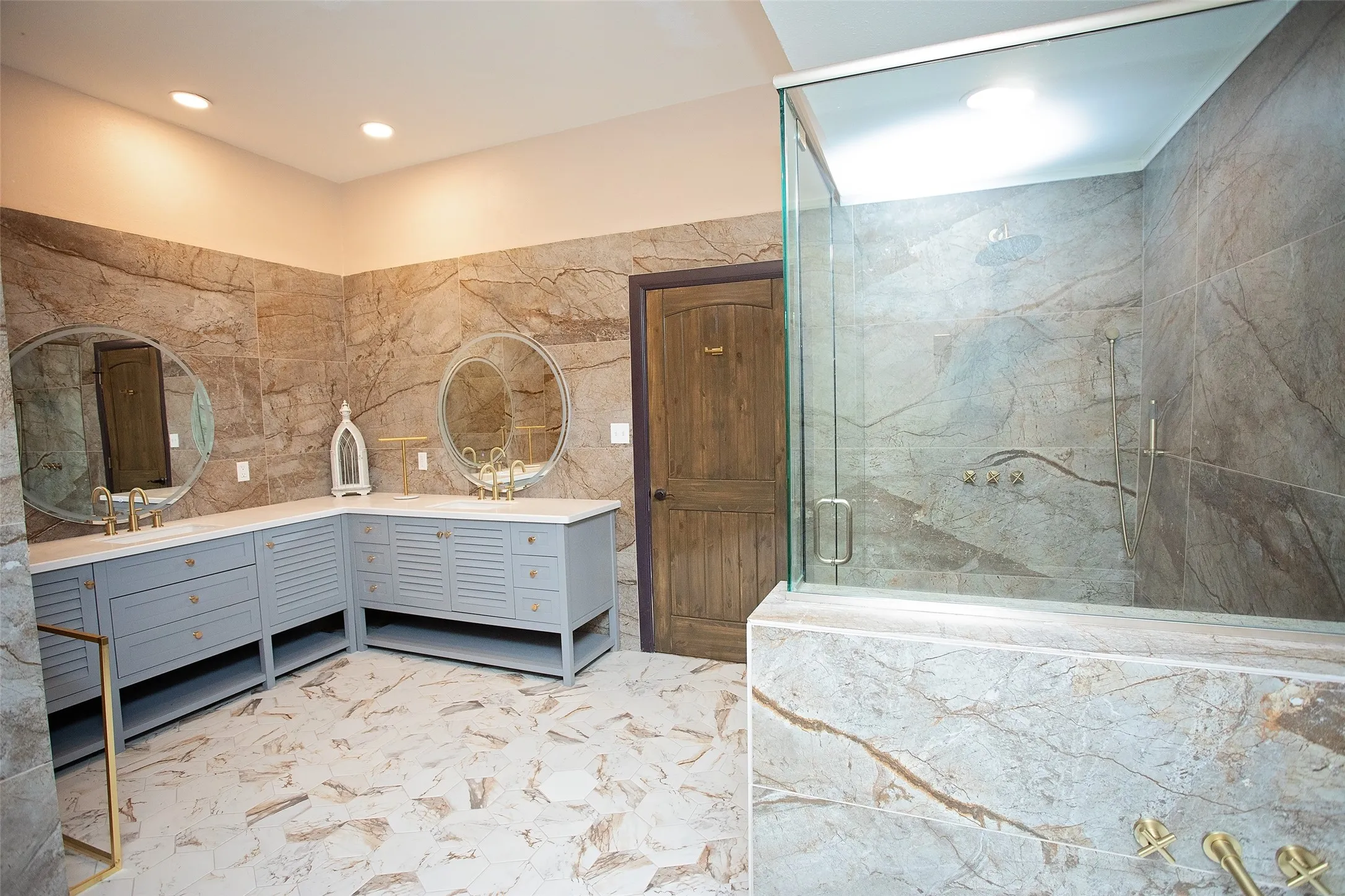 The ensuite bath is designed with scale and style in mind, featuring dual vanities, extensive tile work, a walk-in shower, and a separate soaking tub for a true spa-like experience.
The adjoining dressing area includes generous storage, open shelving, and space for a vanity or dressing station, creating a functional and well-appointed extension of the primary suite.