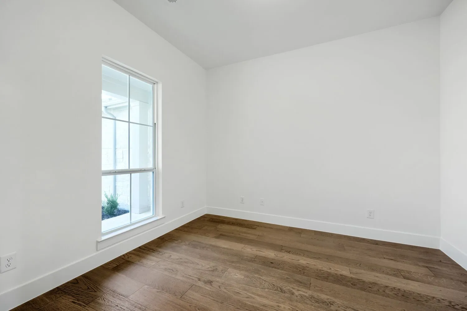 Wood-finish flooring with white wall finishes and a multi-pane window