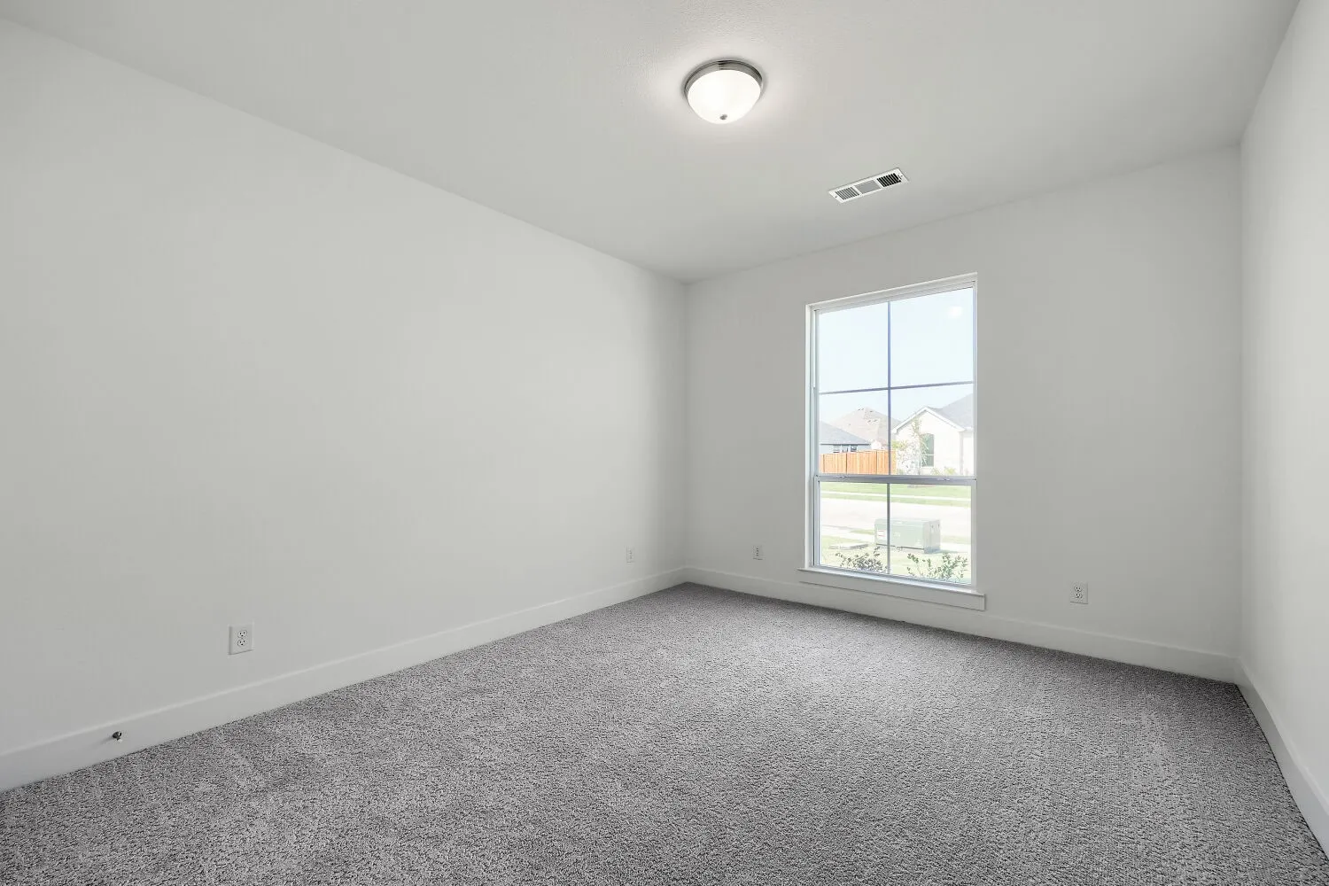 Neutral white wall paint, gray carpeting, single window with white trim, and a ceiling-mounted light fixture
