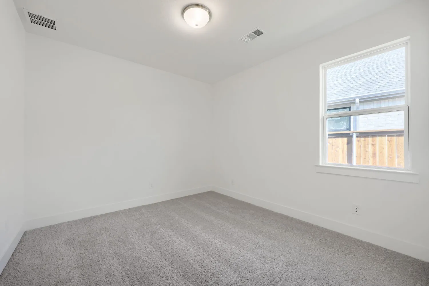 Neutral wall paint, light gray carpeting, and a window with white trim