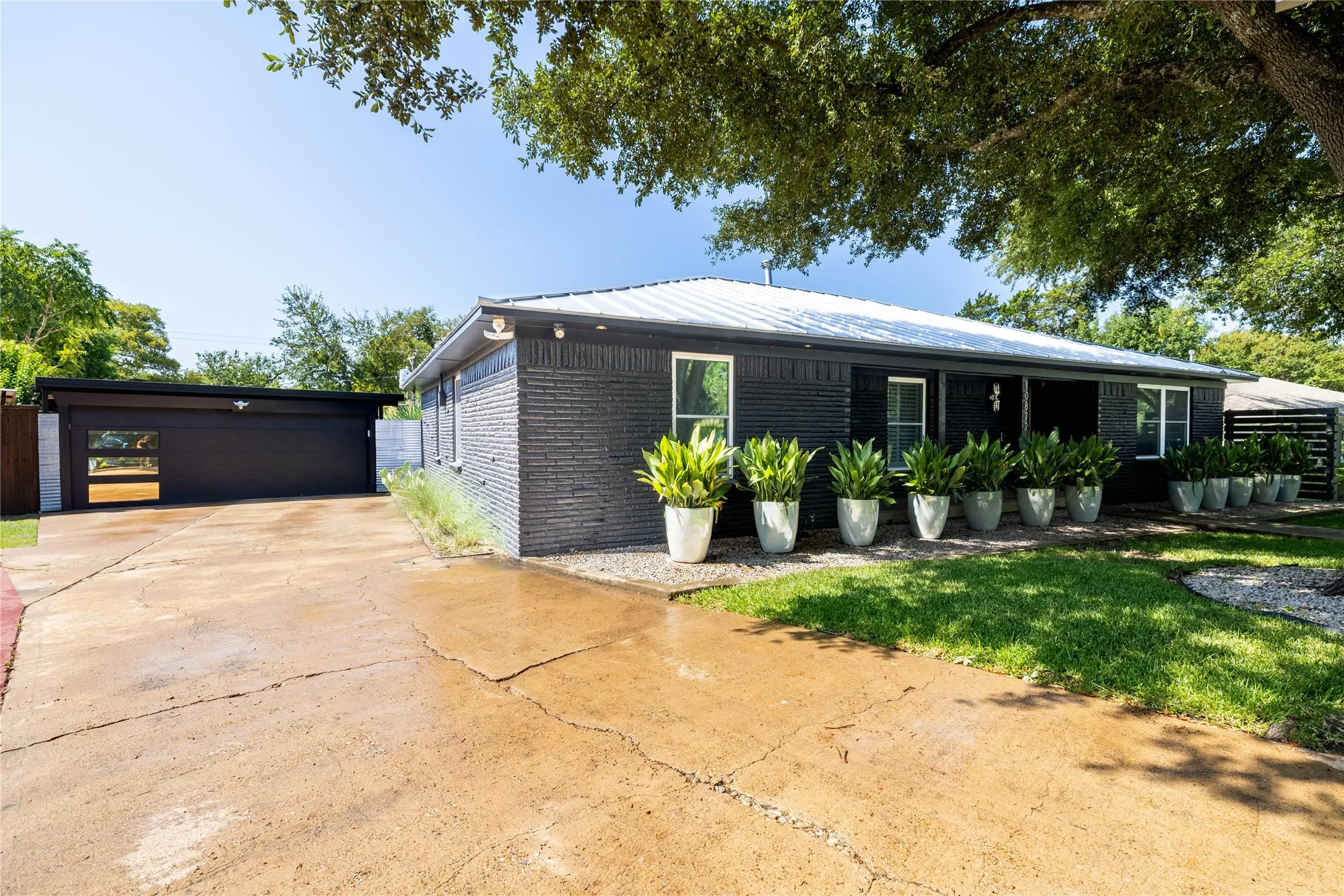 Contemporary facade featuring dark brick siding, white window trim, and a white metal roof