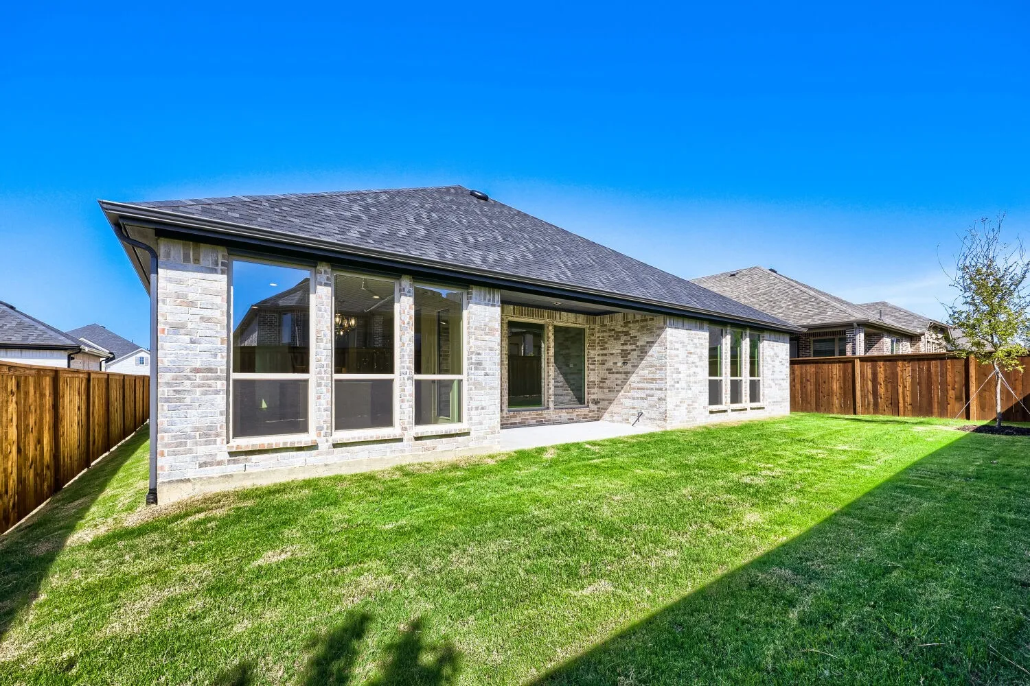 Expansive backyard featuring a lush lawn, privacy fencing, and a covered patio