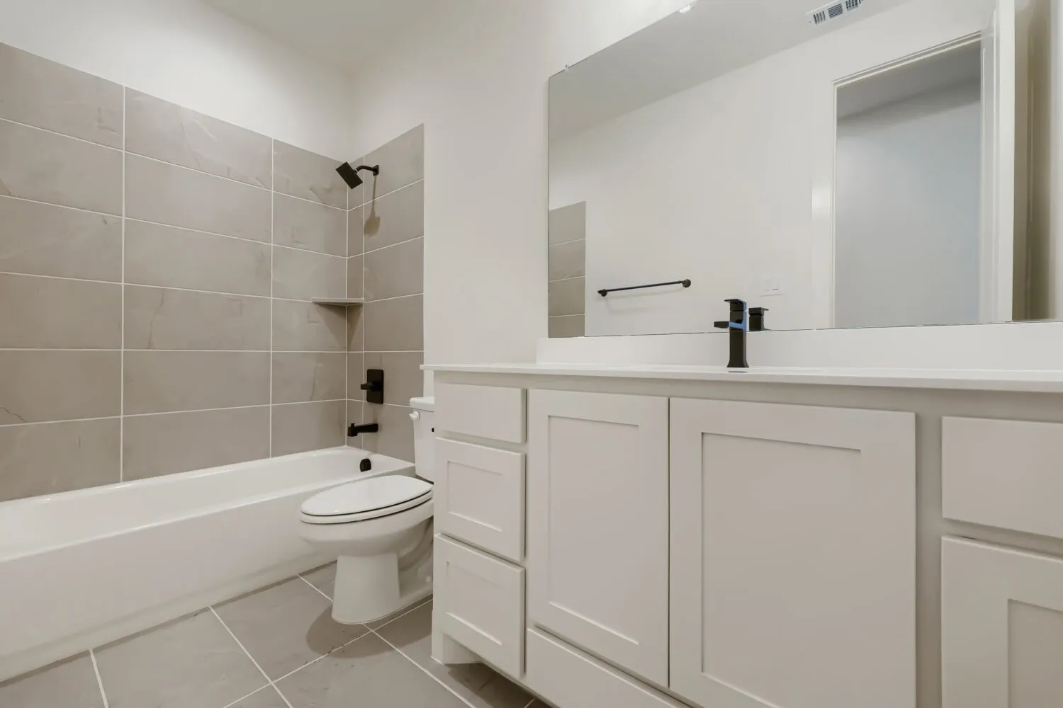 Modern bathroom featuring a white vanity with multiple storage drawers, quartz countertop, and matte black faucet hardware