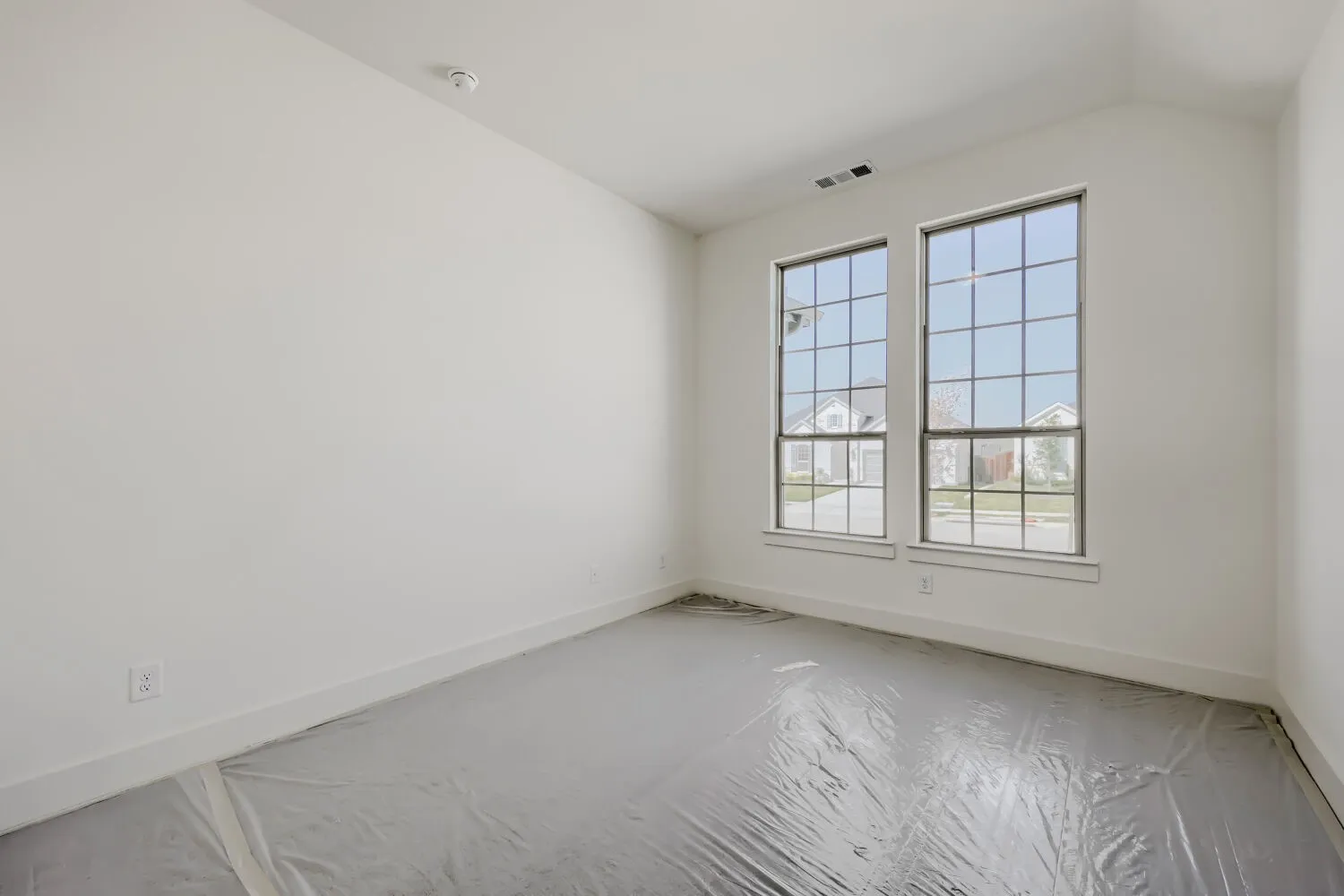 Twin pane windows with grid details, white trim, and a high ceiling