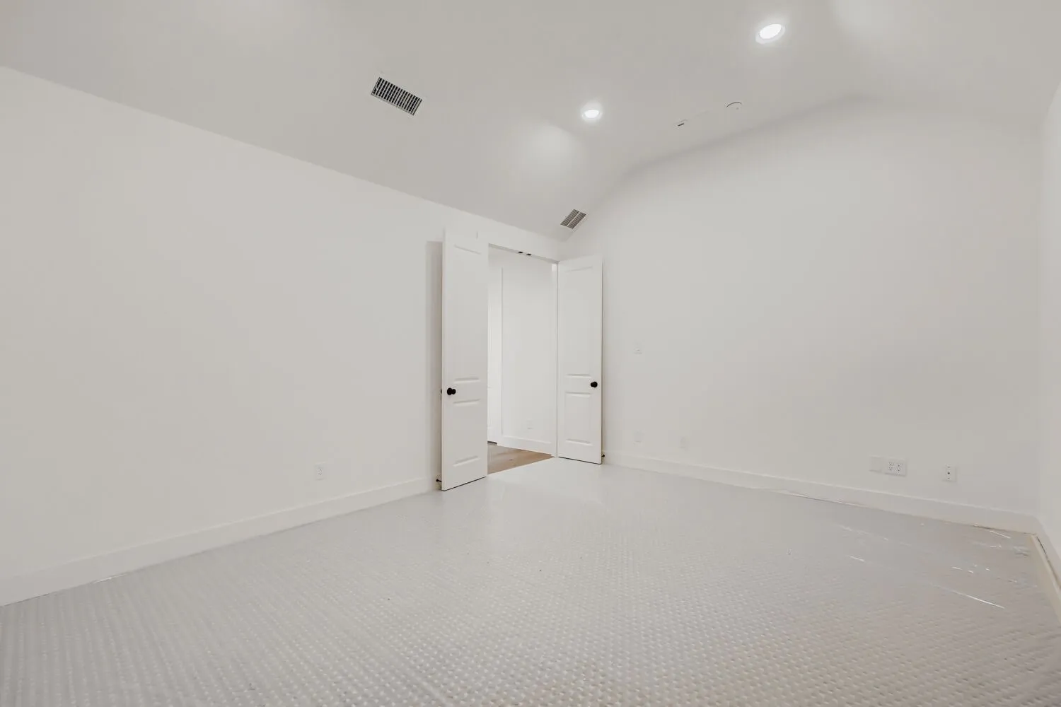 Bright interior with vaulted ceiling, recessed lighting, white walls, and a textured floor covering