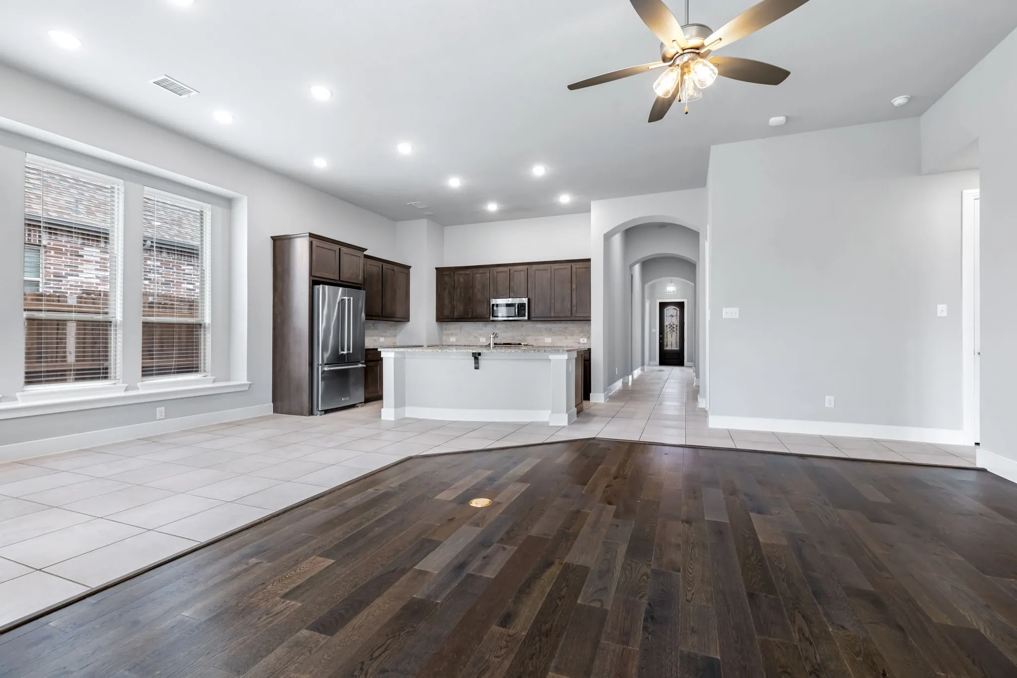 Open-concept living area with dark wood-finish flooring, recessed lighting, and a ceiling fan