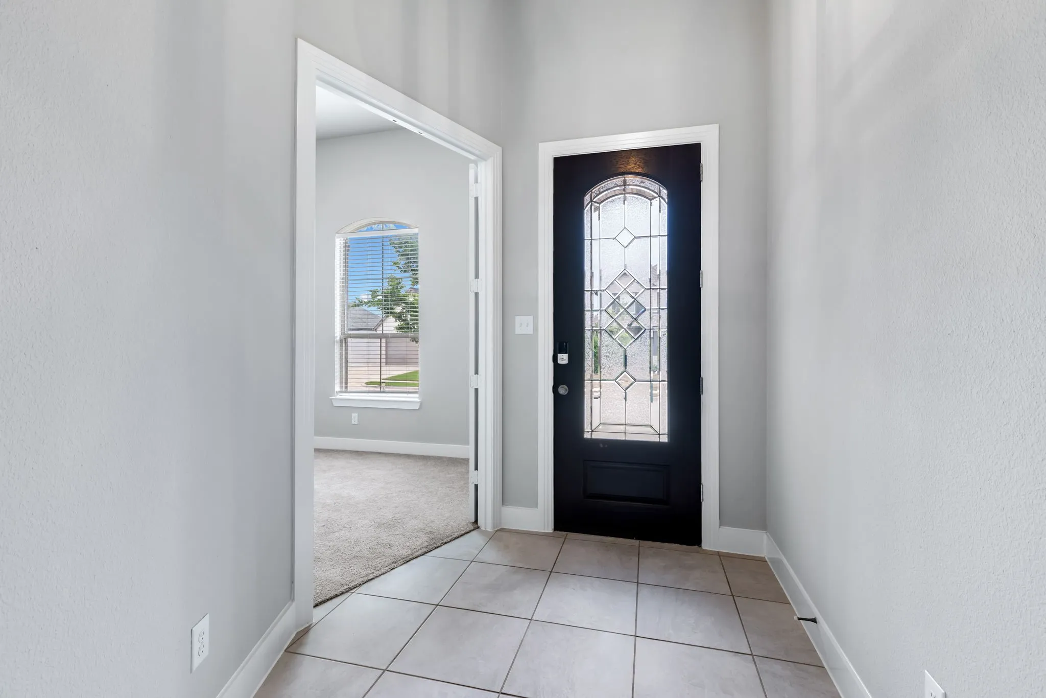 Entryway featuring tile flooring and a dark-paneled front door with decorative leaded glass
