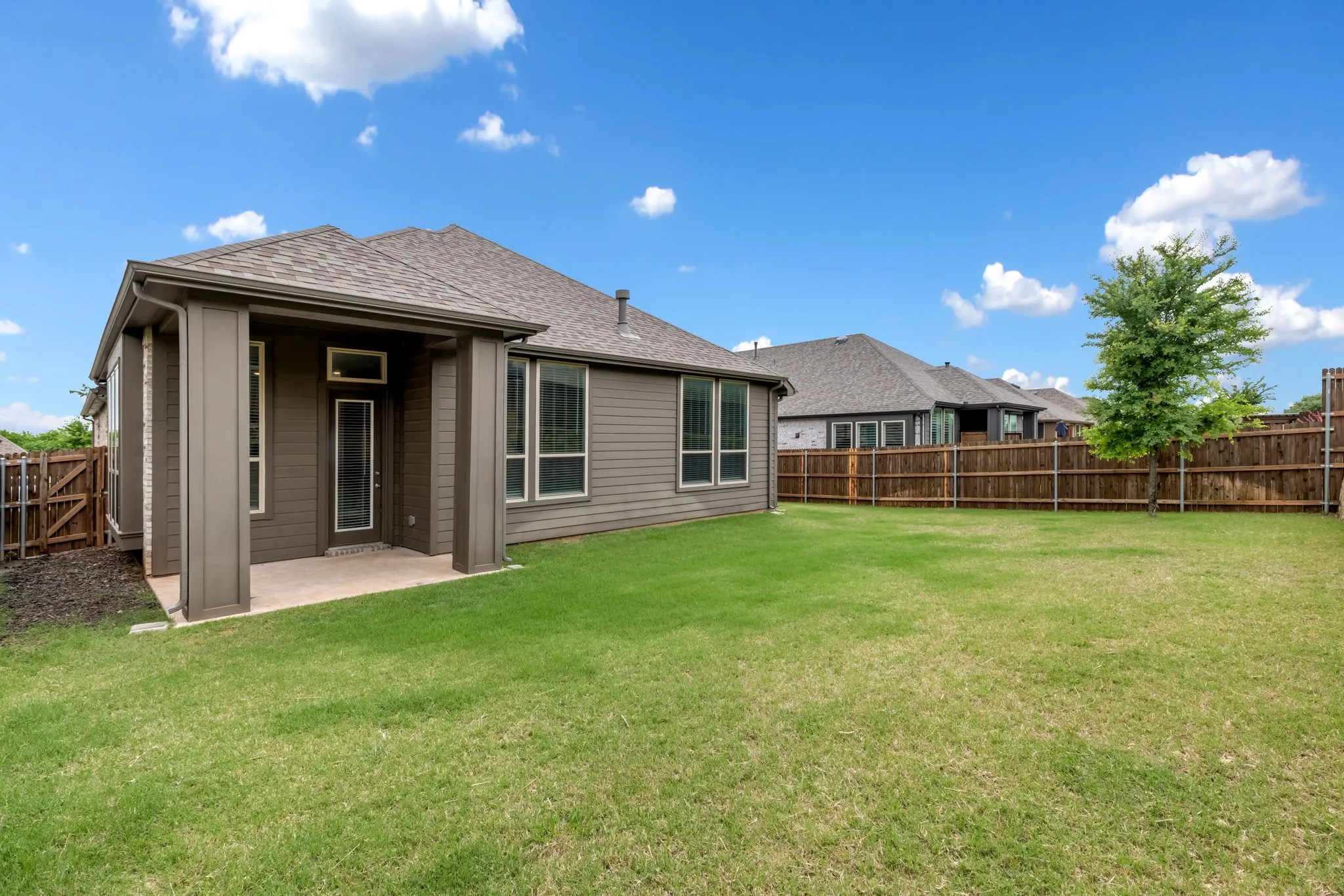 Expansive backyard featuring a covered patio, manicured lawn, and a full privacy fence