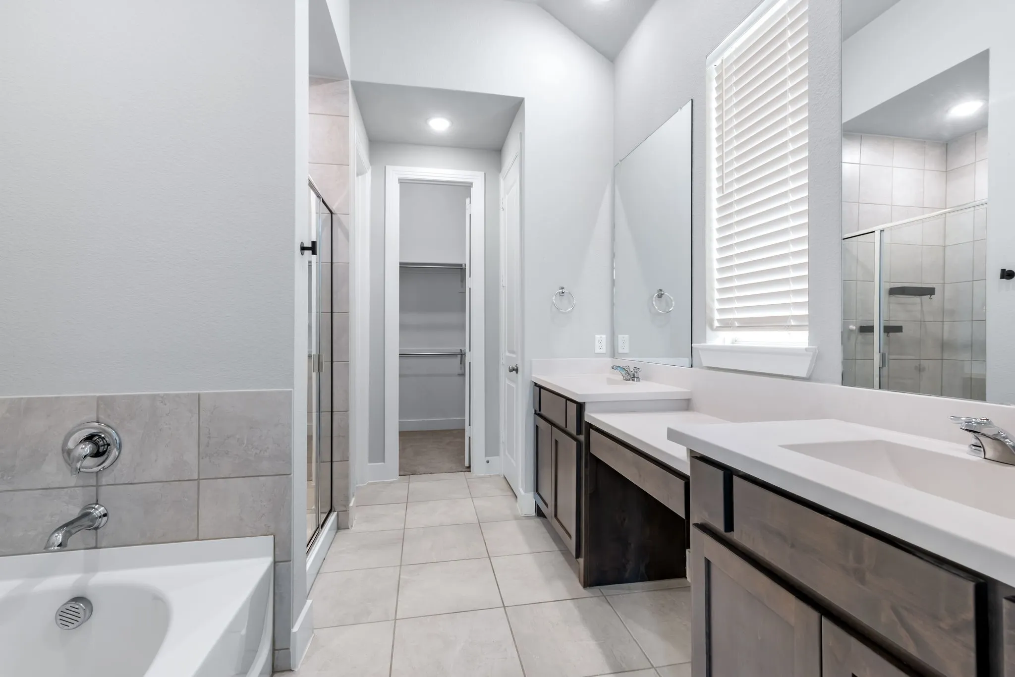 Spacious bathroom featuring a dual vanity with white countertops, undermount sinks, and wood-finish cabinetry