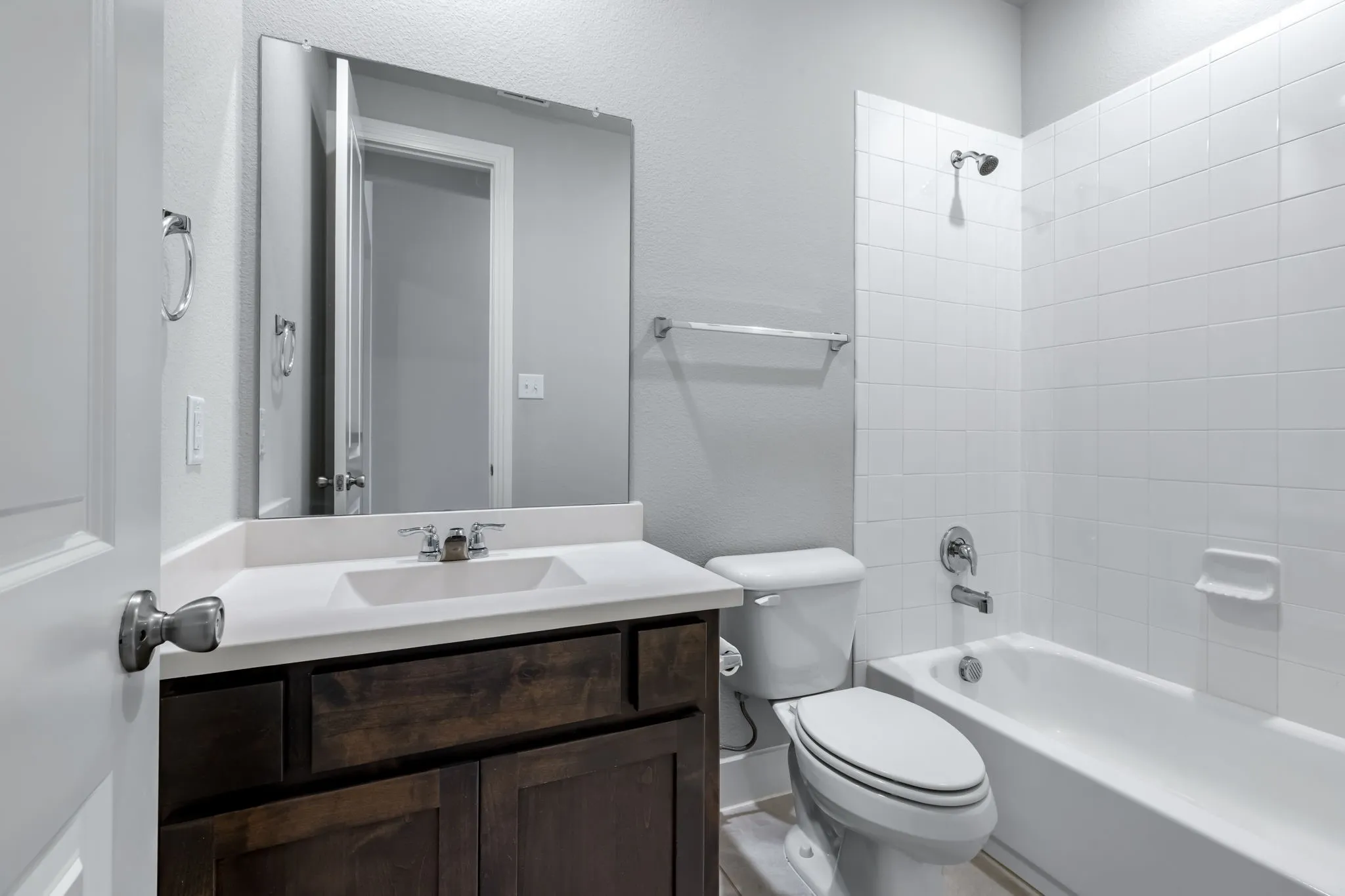 Bathroom featuring a dark wood-finish vanity with a white countertop, undermount sink, and a framed mirror