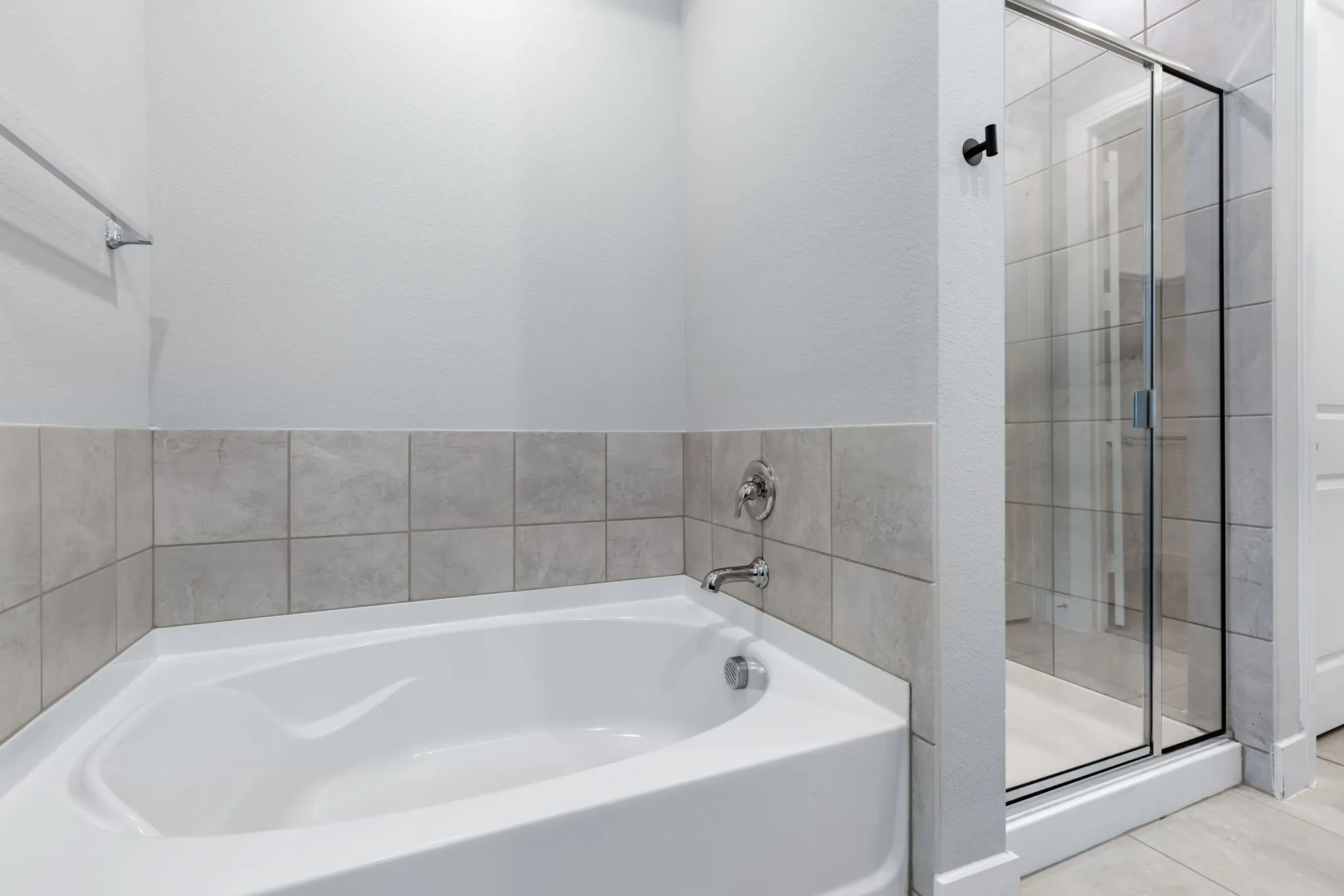 Bathroom featuring a white soaking tub with chrome fixtures, and a glass-enclosed shower with tiled walls