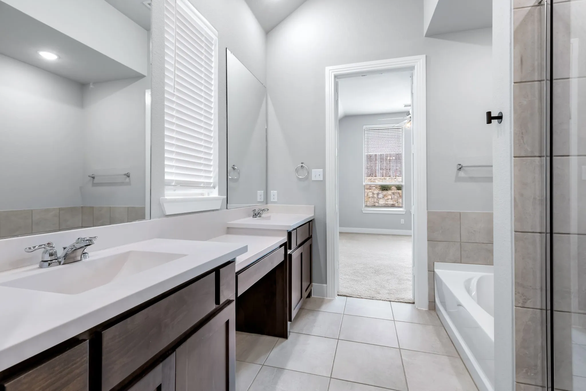 Dual vanity with undermount sinks, white countertops, and wood-finish cabinetry