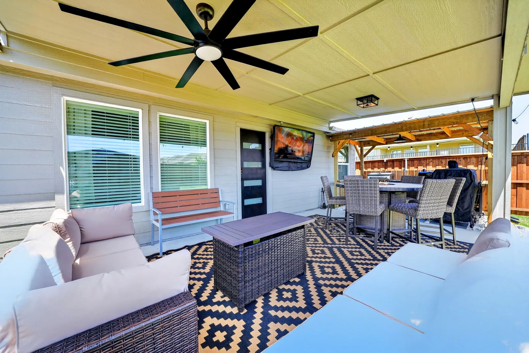 Covered patio featuring a large ceiling fan, recessed lighting, and a mounted television