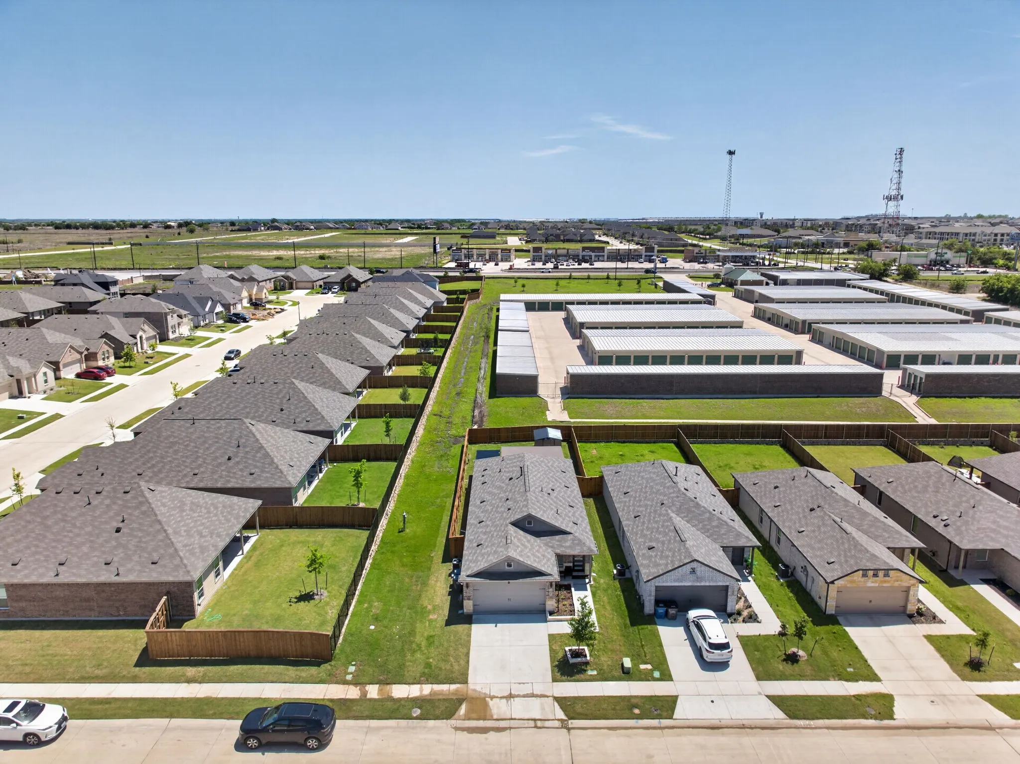 Residential street with single-story homes featuring attached garages, fenced backyards, and manicured lawns