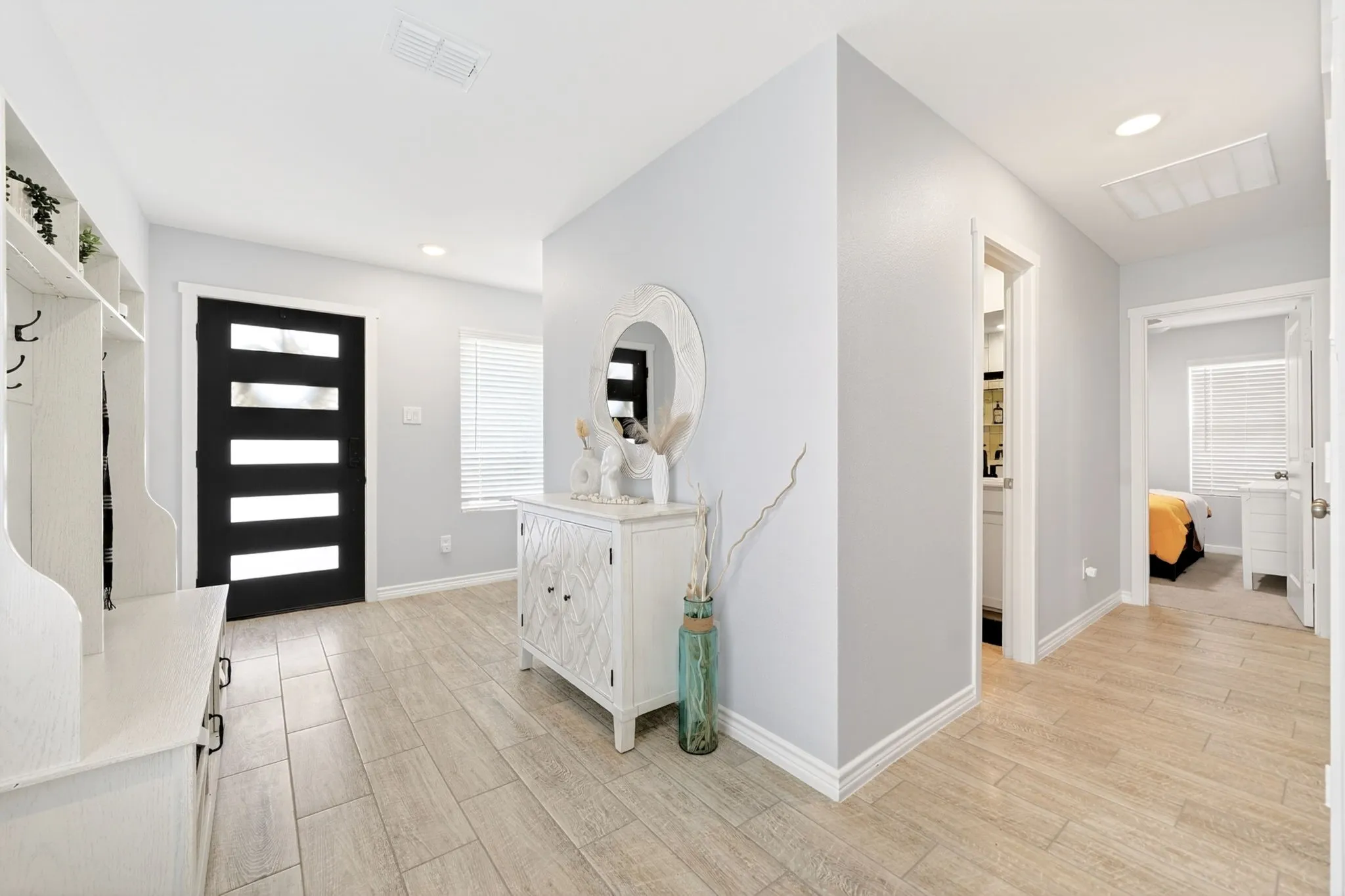 Entryway featuring wood-finish tile flooring, a contemporary black entry door with frosted glass panels, and recessed lighting
