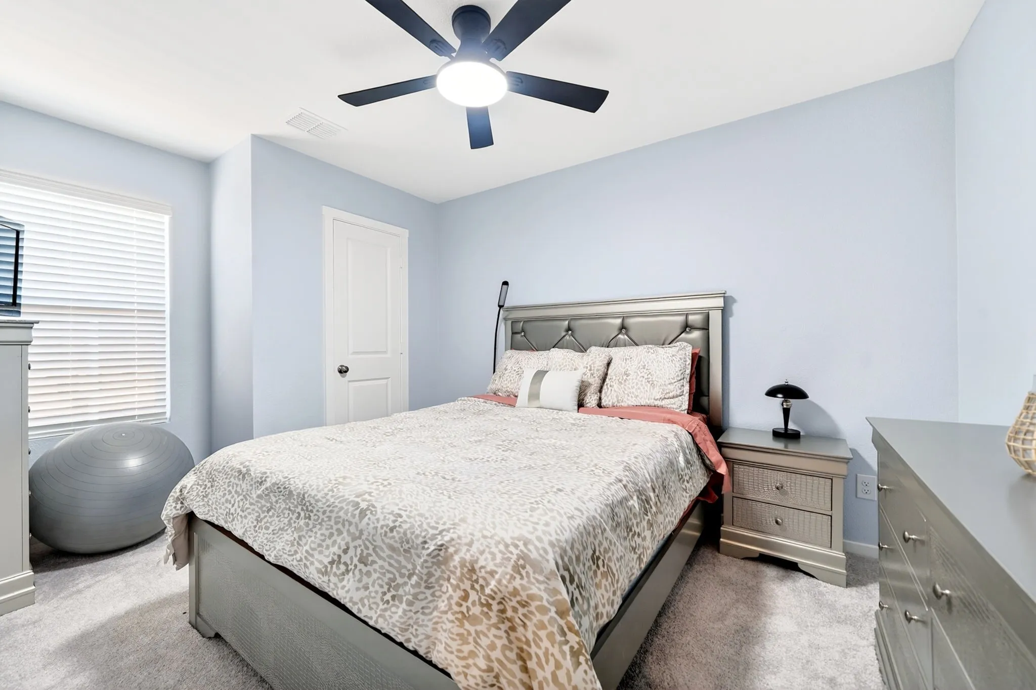 Bedroom featuring light blue wall paint, gray carpet flooring, and a ceiling fan with integrated lighting