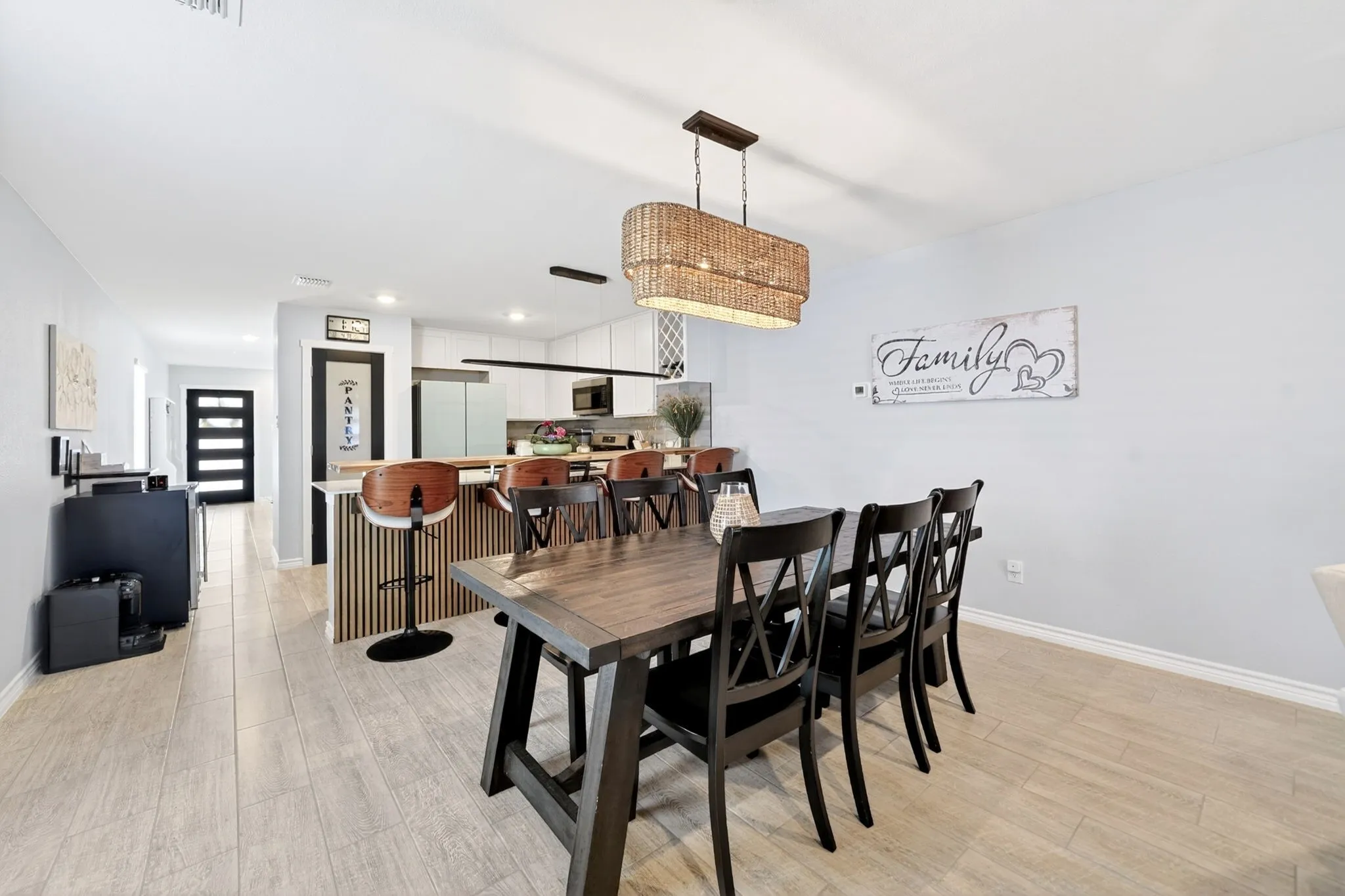 Dining area featuring plank-style flooring, a woven pendant light fixture, and a dark wood-finish dining table