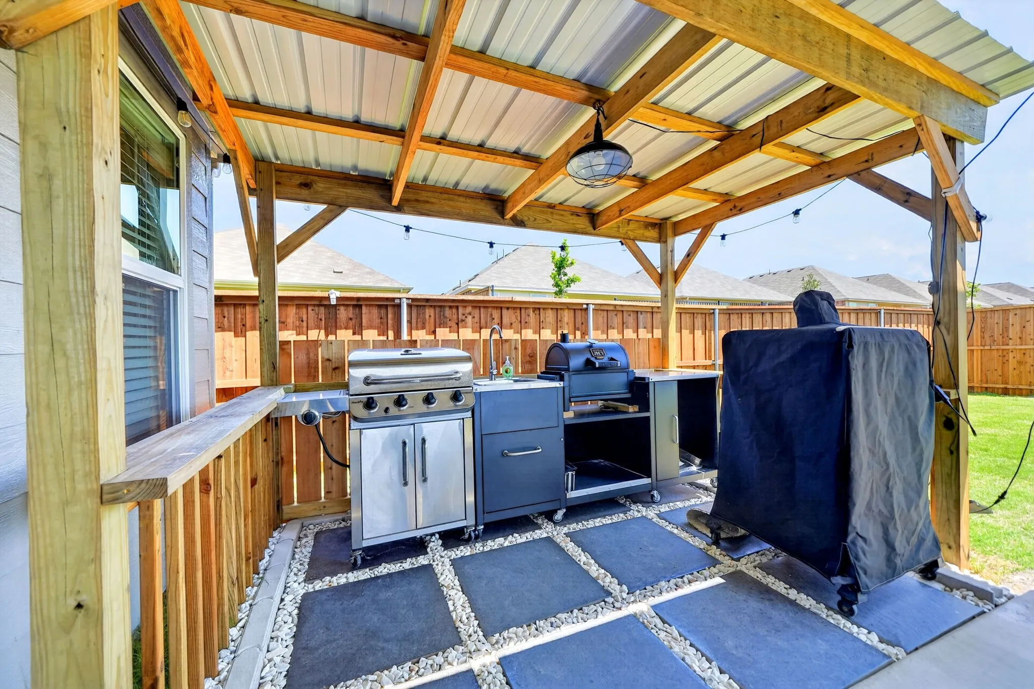 Covered patio with exposed wood beams and a corrugated metal roof