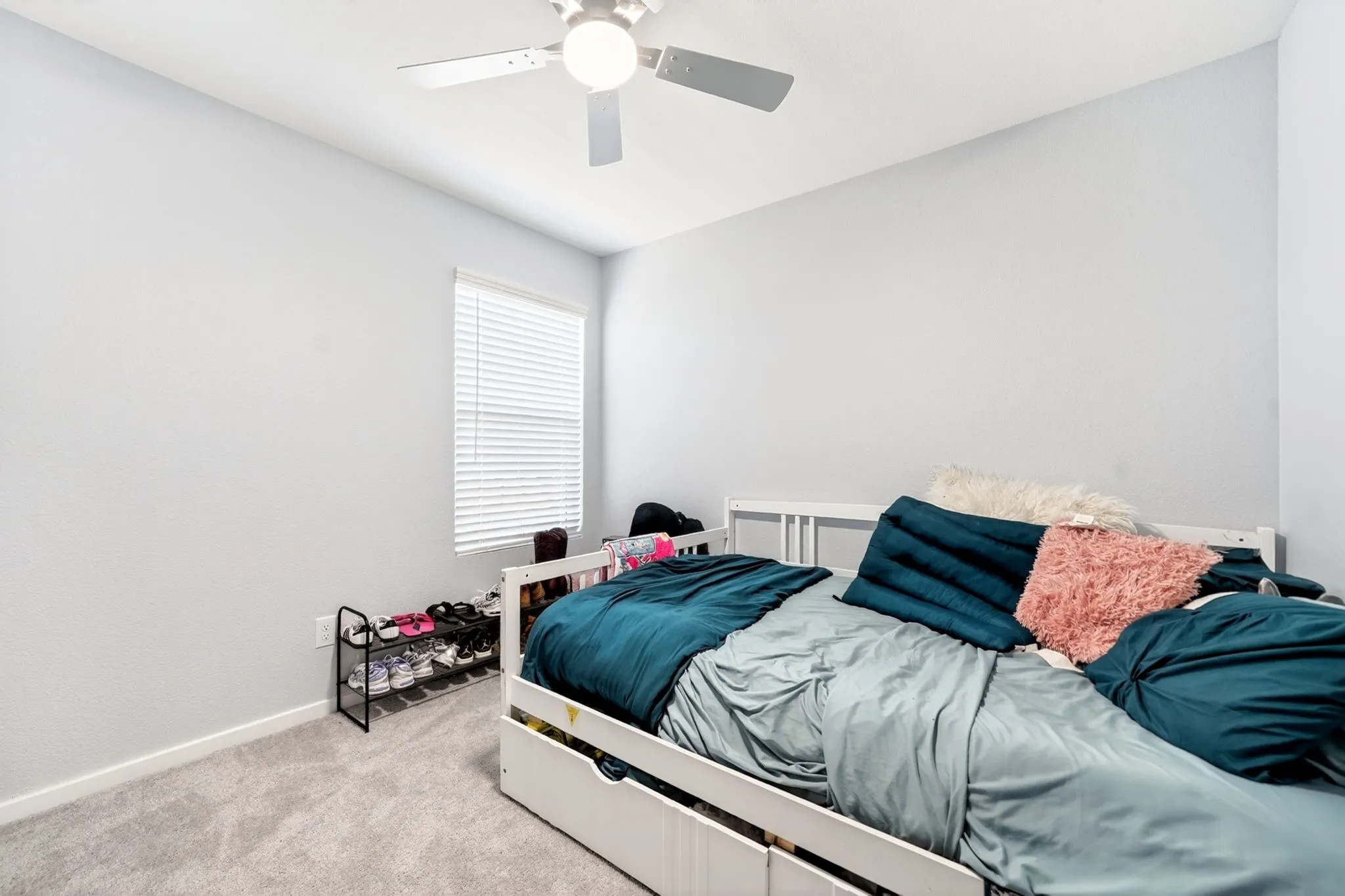 Carpeted bedroom featuring light gray walls and a single window with horizontal blinds