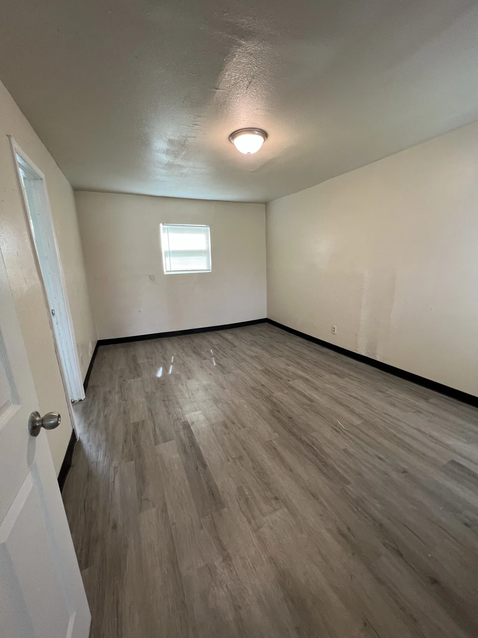 Room featuring wood-finish flooring, a flush-mount ceiling light fixture, a window with blinds, and painted walls