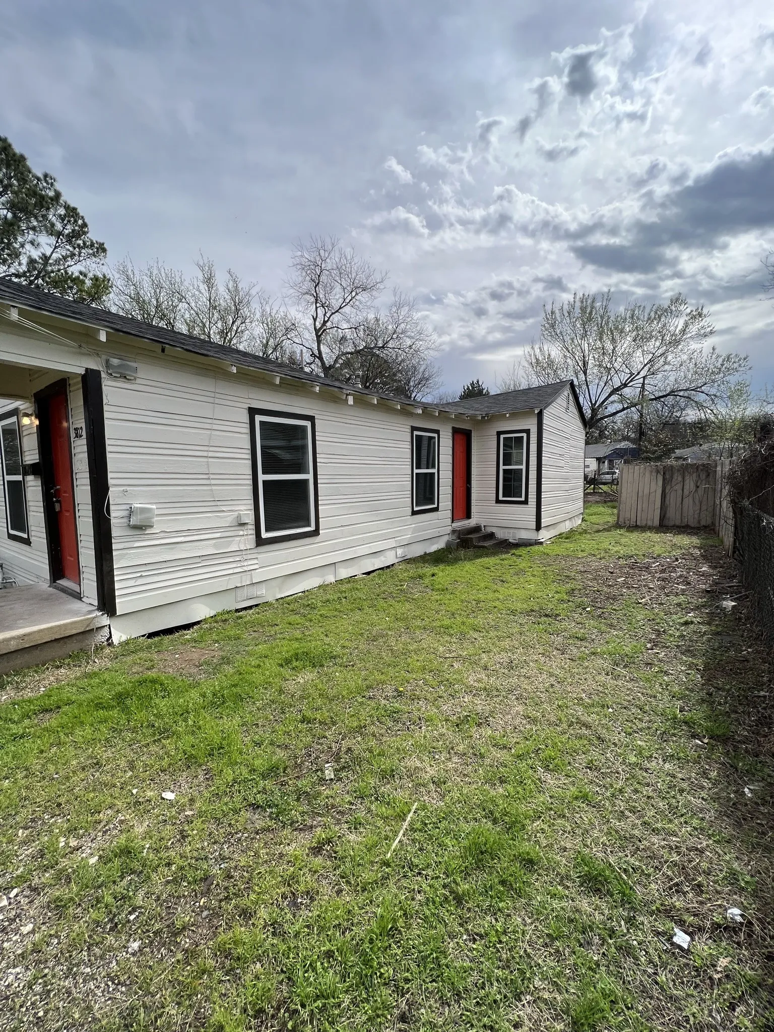 Single-story residence featuring light-colored siding and contrasting black window trim