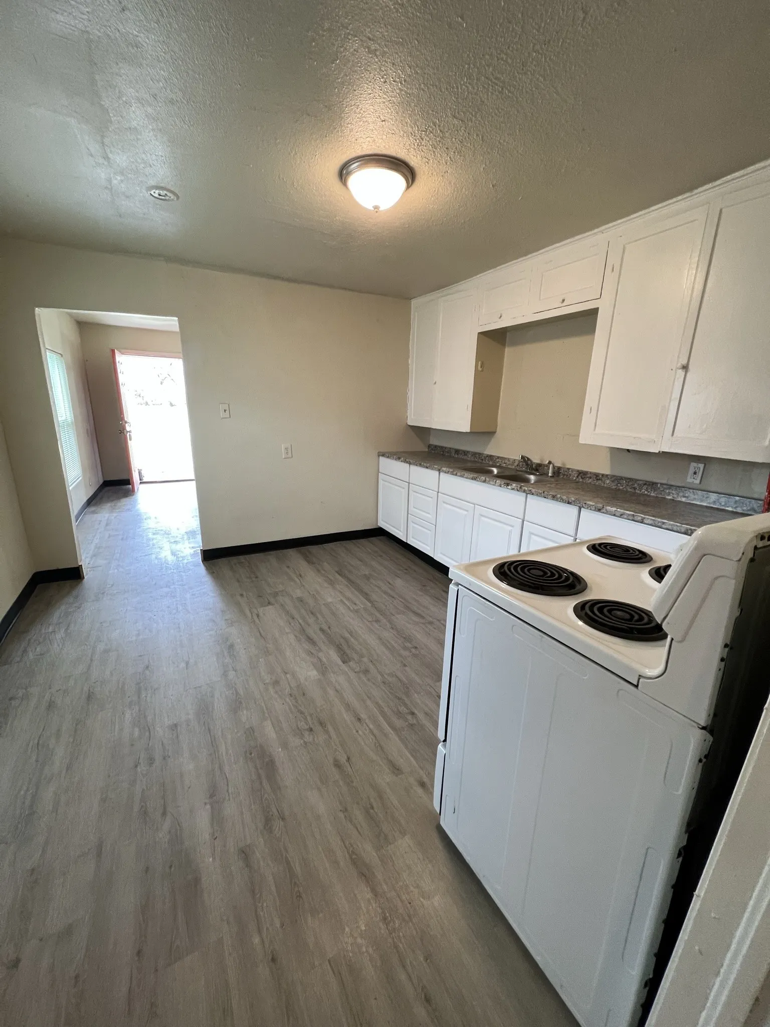 Kitchen featuring white cabinetry with brushed nickel hardware, a stainless steel sink, and a white electric range