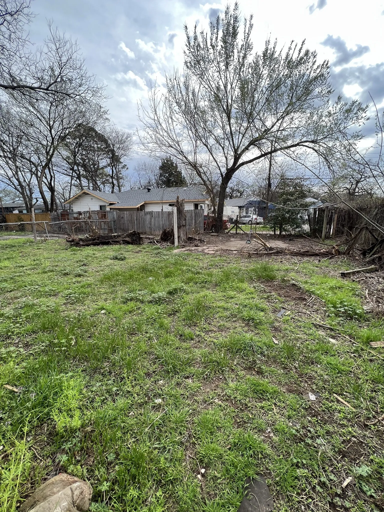 Expansive grassy parcel featuring mature trees, partial fencing, and a natural landscape