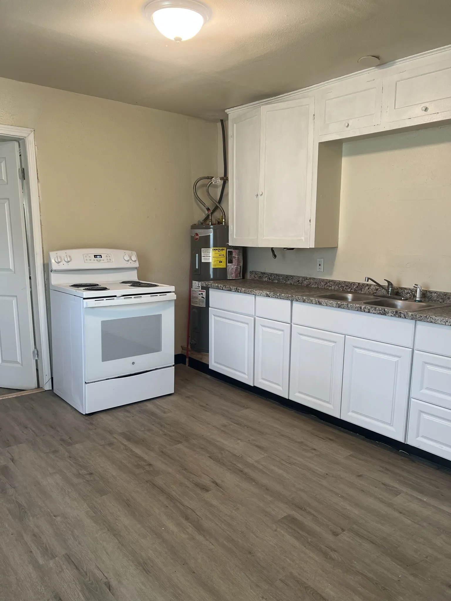 Kitchen featuring white cabinetry, gray speckled countertops, and a double basin stainless steel sink