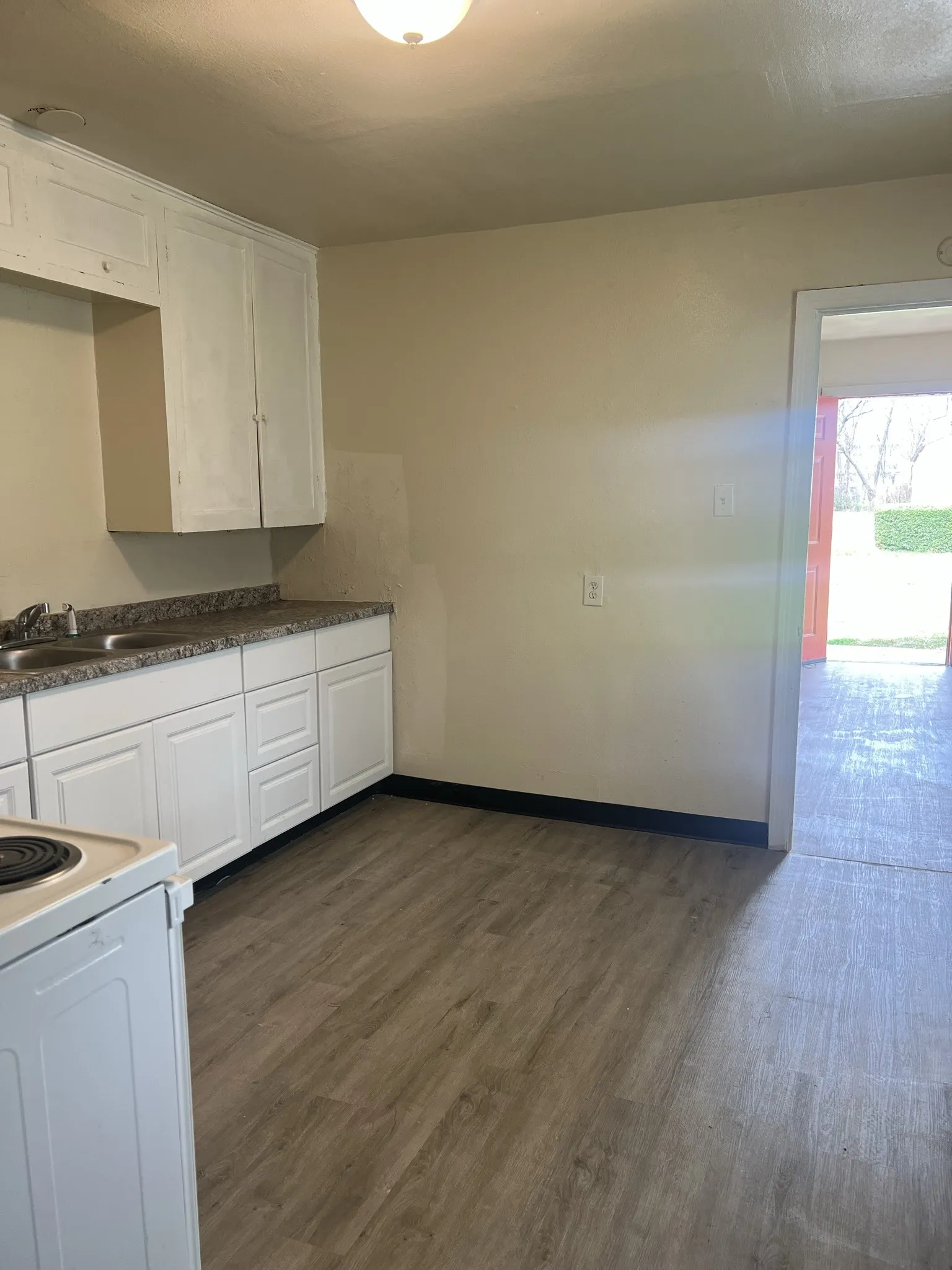 Kitchen featuring wood-finish flooring, white cabinetry, a double basin sink, and granite-look countertops