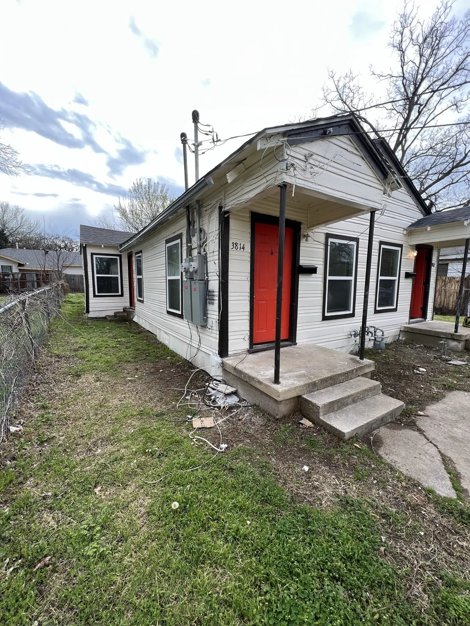 White siding exterior with black trim accents and a vibrant red front door
