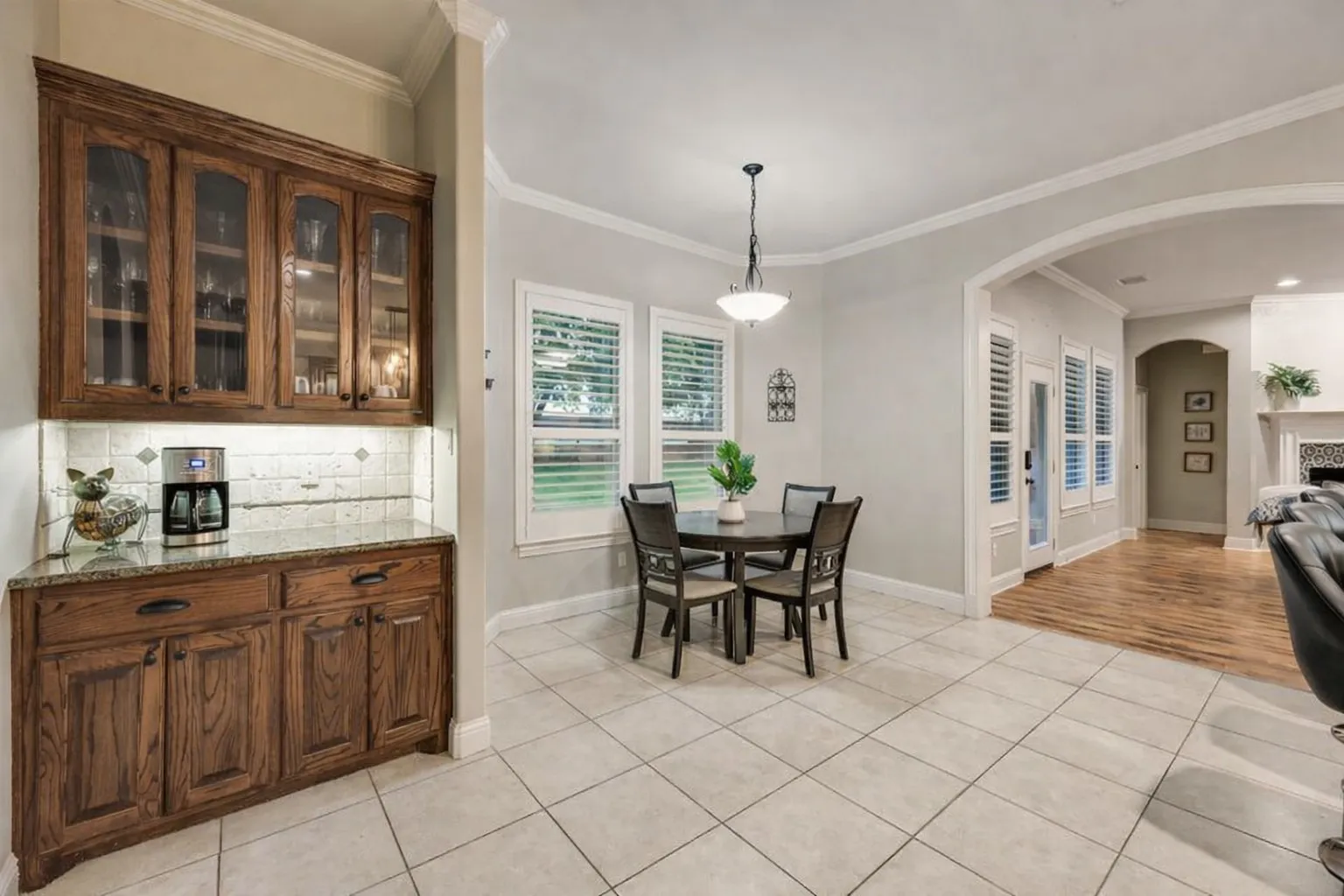 Built-in dry bar featuring wood cabinetry, glass-front upper cabinets, and a stone countertop