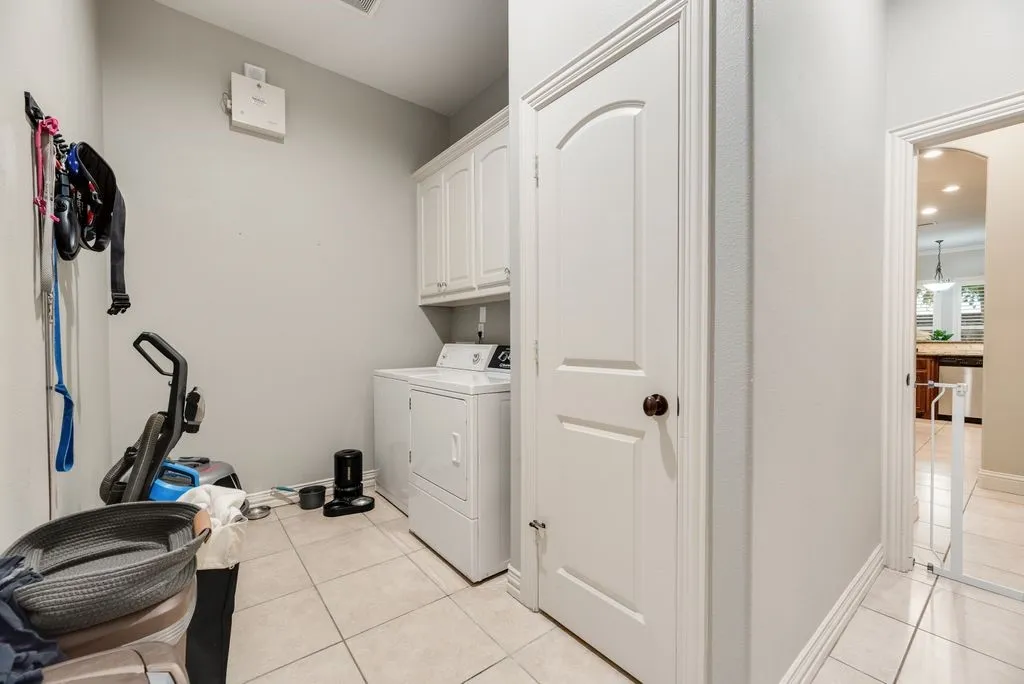 Dedicated utility space featuring tile flooring, white shaker-style cabinetry, and a white washer and dryer