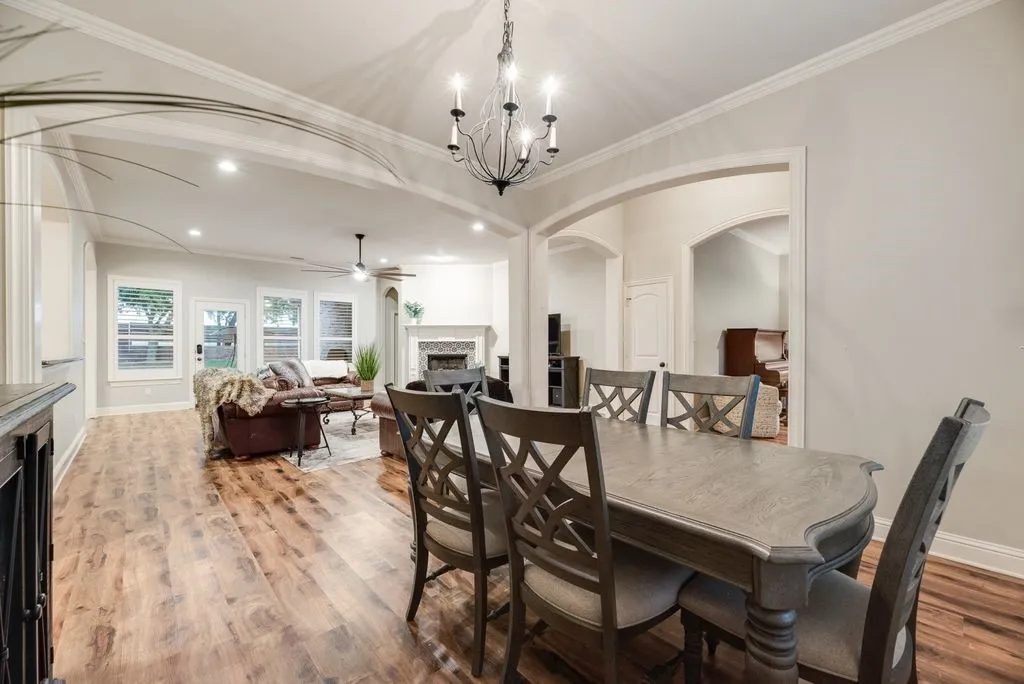 Open-concept living space featuring wood-finish flooring, recessed lighting, and a prominent chandelier