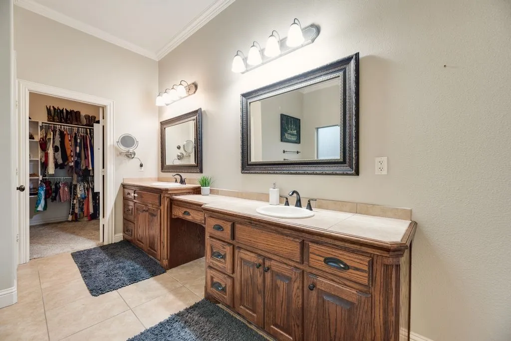 Primary Bathroom, Dual wood-finish vanities with integrated sinks and tile countertops sit across from the Oversized garden tub & Separate shower. The oversized is just beyond.