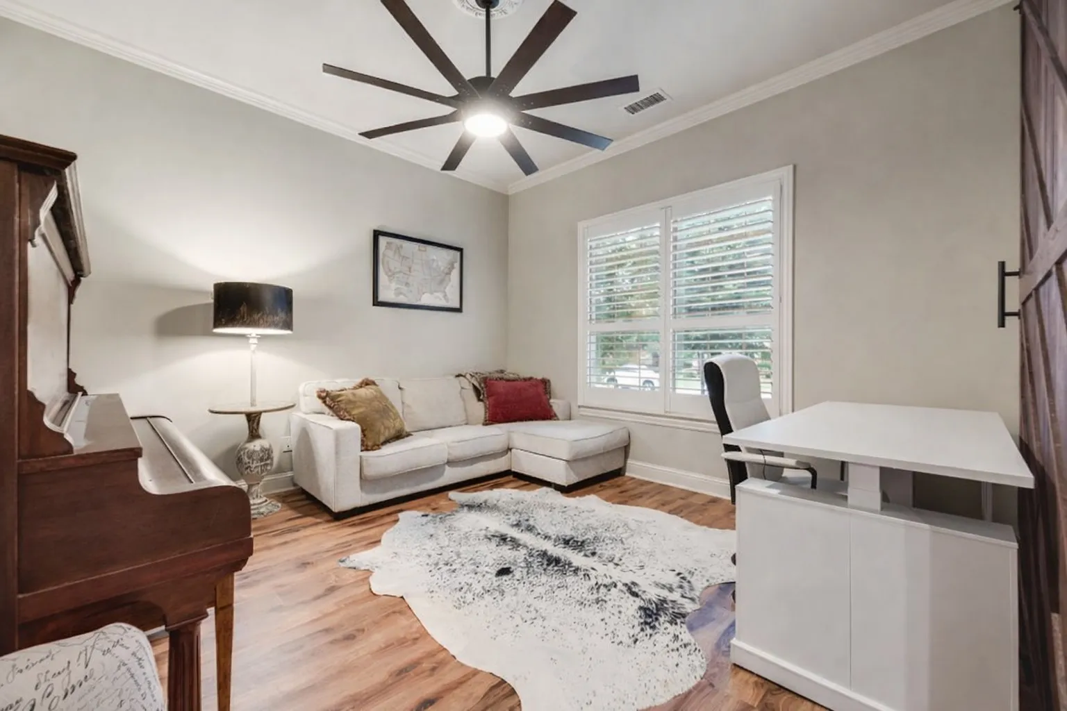 Spacious room featuring wood-finish flooring, a modern ceiling fan, and crown molding