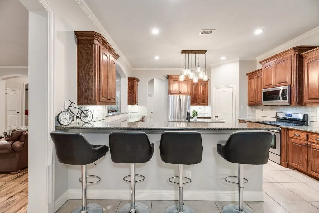 Kitchen featuring a central island with bar seating, wood cabinetry, stainless steel appliances, a tile backsplash, and recessed lighting