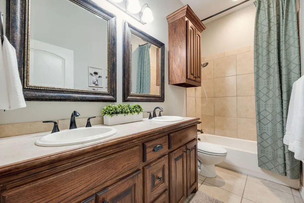 Bathroom vanity featuring dual sinks, oil-rubbed bronze fixtures, and framed mirrors