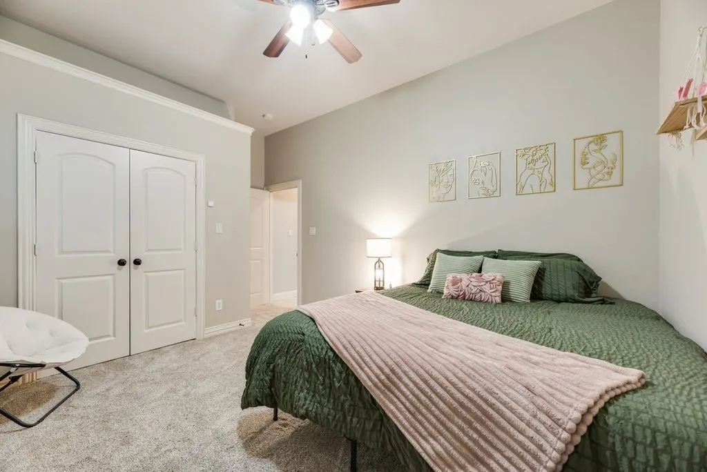 Bedroom 4: Carpeted room featuring a ceiling fan with light fixture, double-door closet, and crown molding
