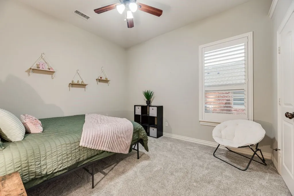 Bedroom 4: Carpeted room featuring a ceiling fan, a window with plantation shutters, and a paneled door