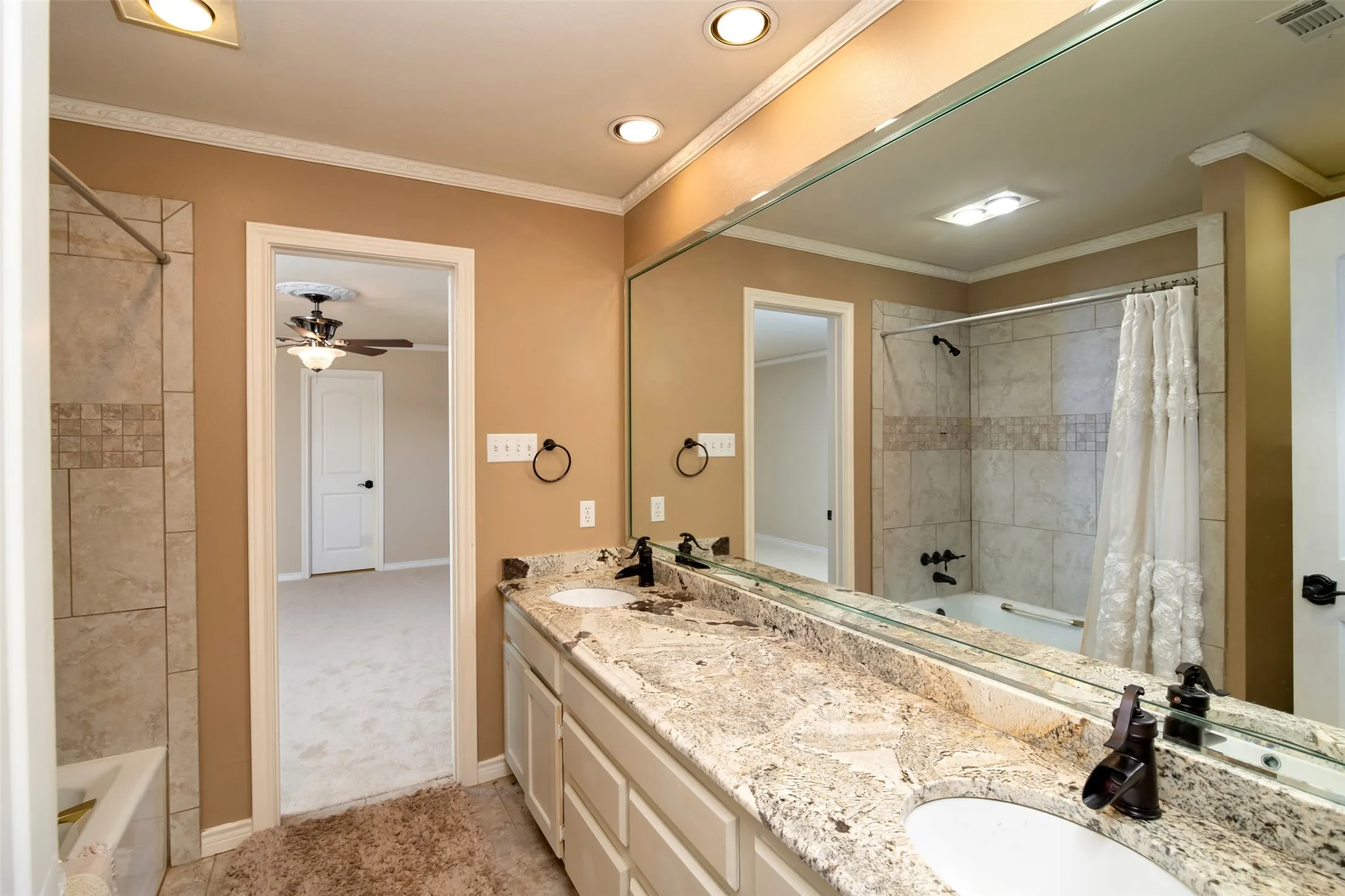 Bathroom featuring a dual vanity with a granite countertop, white under-mount sinks, and oil-rubbed bronze fixtures