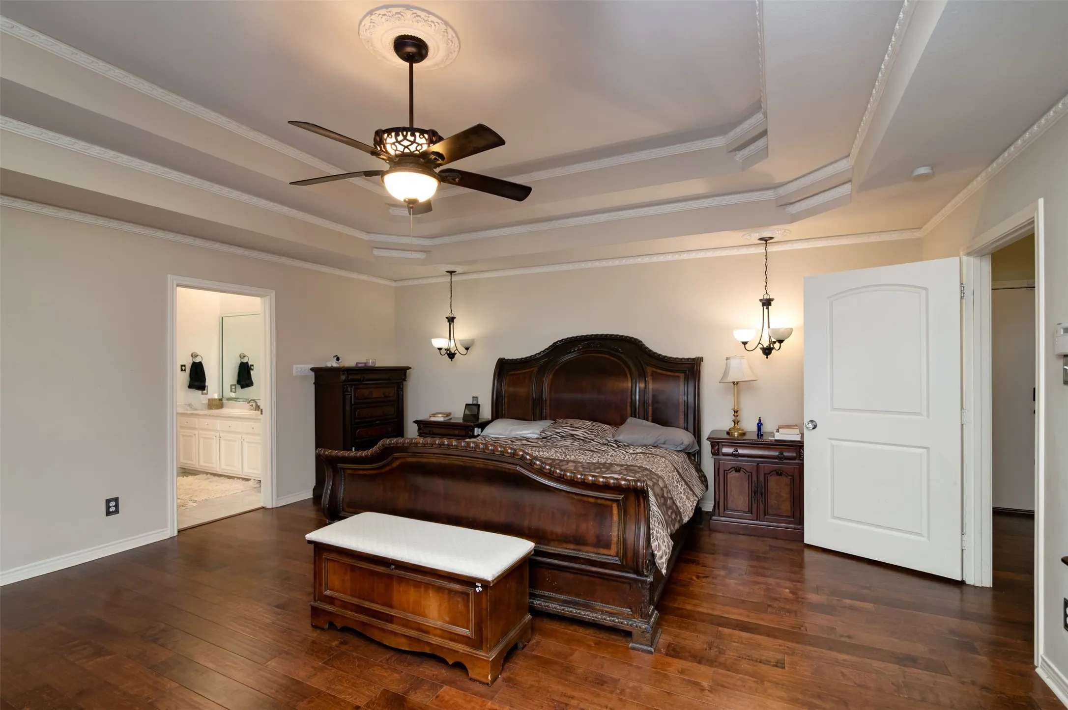 Spacious room featuring wood-finish flooring, a coffered ceiling with crown molding, a decorative ceiling fan, and two wall sconces
